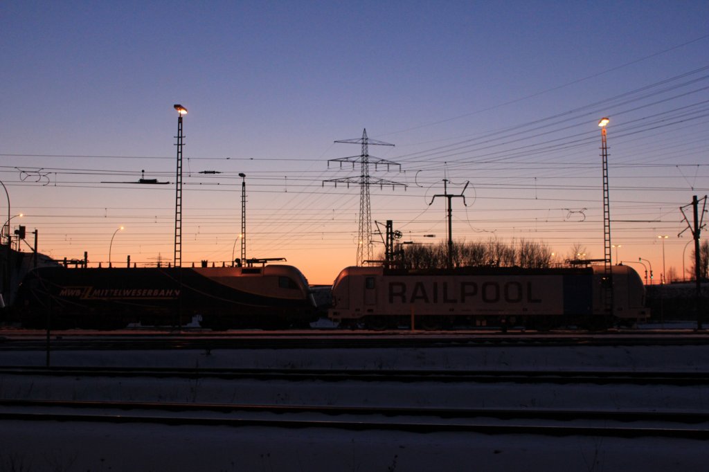 Die Sonne geht ber evb Logistik Mittelweserbahn 182 912 und Railpool 193 802 am 12.03.2013 in Waltershof unter.