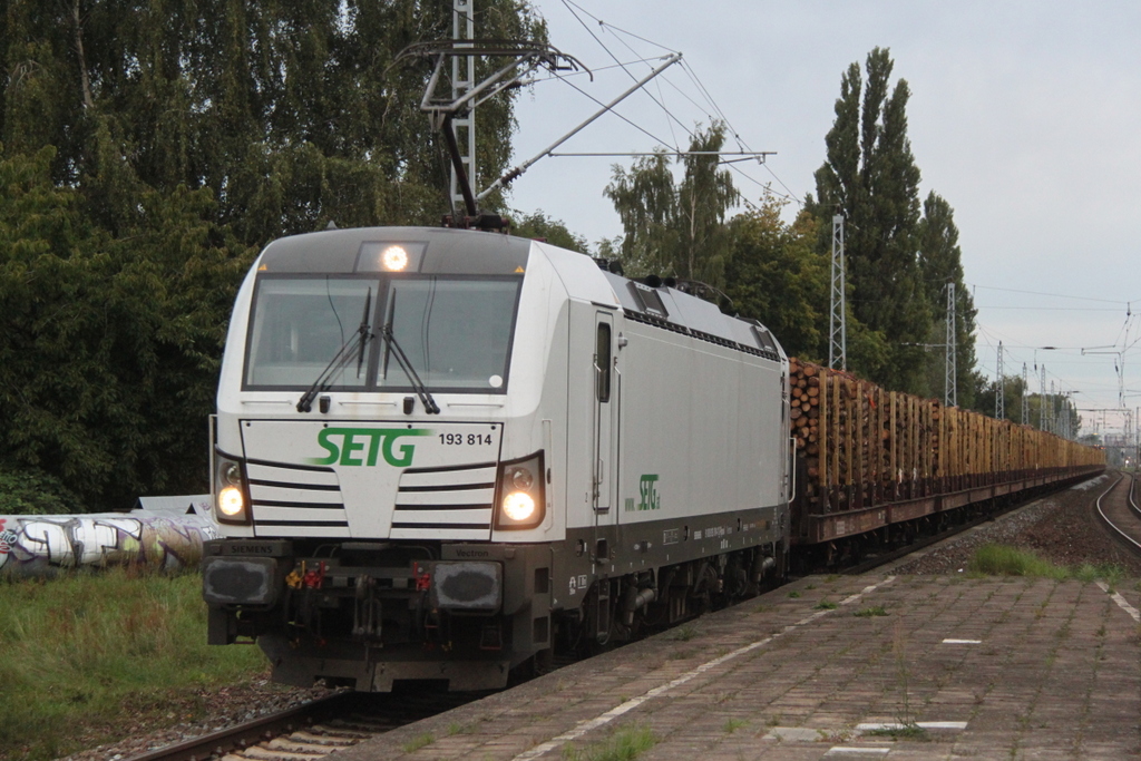 193 814-1 mit Holzzug von Rostock-Bramow nach Stendal-Niedergrne bei der Durchfahrt am 16.09.2015 im Haltepunkt Rostock-Holbeinplatz.