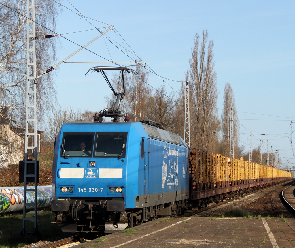 145 030-7 mit Holzzug von Rostock-Bramow nach Stendal-Niedergrne bei der Durchfahrt im Haltepunkt Rostock-Holbeinplatz.21.04.2013