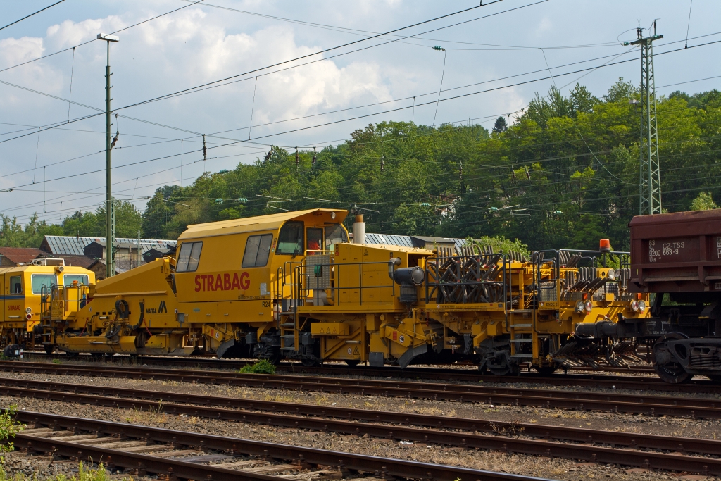 Die MATISA R24 Schotterplaniermaschine der STRABAG Rail GmbH (Schweres Nebenfahrzeug Nr. 99 80 9225 001-3 D-STRA) ist am 30.05.2012 in Betzdorf/Sieg abgestellt.

Die Maschine wurde 2009 von der MATISA Matriel Industriel S.A. in Crissier (Schweiz) unter der Fabrik-Nr. 47051 gebaut.

Die R 24 ist eine Hochleistungs-Schotterplaniermaschine auf Drehgestellen, speziell konzipiert fr den Bau und den Unterhalt der Hochgeschwindigkeitsstrecken. Ihre beiden Kehrbesen garantieren eine ausgezeichnete Kehrleistung bei einer Geschwindigkeit von +/- 6 km/h.
Der erste Kehrbesen fr die Strecke, bestckt mit einem Lngsfrderband, sammelt den berschssigen Schotter auf den Schwellen und transportiert ihn mit dem Frderband  in das15 m groe Silo. So kann berschssiger Schotter zurck gewonnen und in Bereichen mit Schottermangel verteilt werden. Die 4 unabhngige Schotterhosen unter dem Silo verteilen den Schotter vor den Pflgen, welche diesen im gleichen Arbeitsgang auf dem Gleis verteilen. Der zweite Kehrbesen, fr Weichen, ausgerstet mit einem Querfrderband, verteilt den Schotter zur linken und rechten Seite. Mit seiner sehr gerumigen Kabine, die auch an spezifische Kundenwnsche angepasst werden kann, bietet die R 24 einen groen Komfort.

Die Maschinen sind mit einem hydrostatischen Fahrantrieb ausgestattet, der einfach und bequem zu bedienen ist. Die Fahrgeschwindigkeit kann ohne Rucken durch Schaltvorgnge gesteuert werden. Das ruckfreie Fahren erhht den Komfort und ist ein Gewinn fr Mensch und Maschine, und das jeden Tag. Ein weiterer Vorteil des hydrostatischen Fahrantriebs ist, dass ein Schlupf der Rder beim Anfahren verhindert wird.

TECHNISCHE DATEN: 
Spurweite: 1.435 mm  (Normalspur)
Achsanzahl: 5 (2 Drehgestellen, eine einzelne Achse)
Achsformel: Bo´ + A1´ + 1
Lnge ber Puffer: 26.500 mm
Drehzapfen- bzw. Achsabstand: 12.500 mm / 8.000 mm
Achsabstand in den Drehgestellen: 1.800 mm
Treib- und Laufraddurchmesser: 920 mm (neu)
Hhe: 4.263 mm
Breite: 3.050 mm
Eigengewicht: 68.420 kg
Anhngelast: - t
Zur Mitfahrt zugel. Personen: 5
Hchstgeschwindigkeit (geschleppt): 100 km/h 
Hchstgeschwindigkeit Eigenfahrt: 25 km/h (nur als Rangierfahrt)
Max. Geschwindigkeit beim Planieren: 15 km/h
Max. Geschwindigkeit beim Kehren: 6 km/h     
Zugelassen ab Streckenklasse: C2 
Kleinster befahrbarer Kurvenradius:  R 250 m  (Fahrzeug allein 90 m)
Min. Radius bei Arbeit: R 190 m
Bremse: 2 x KE-GP (K), Max. 57 t
Dieselmotor:  DEUTZ wassergekhlter V8-Zylinder-Viertakt- Dieselmotor mit Turboaufladung, Ladeluftkhlung, Vierventiltechnik und wassergekhlte Abgasrohre vom Typ DEUTZ BF 8 M 2015 CP 
Motorleistung: 440 kW (598 PS) bei 2.100 U/min
Motorhubraum: 15,9 Liter (Bohrung 132 mm / Hub 145 mm)
Motorgewicht: 1.060 kg
Gre Schottersilo:15 m  (Standard 10 m)
Tankvolumen: 3.000 Liter  (Standard 2 m)

Bemerkung: Laut Prospekt von Matisa kann die Maschine in Eigenfahrt auch 100 km/h schnell fahren (dann hat sie nur 2 Achsen angetrieben), aber laut Anschriftentafel ist eine Eigenfahrt nur als Rangierfahrt mit 25 km/h zugelassen.
