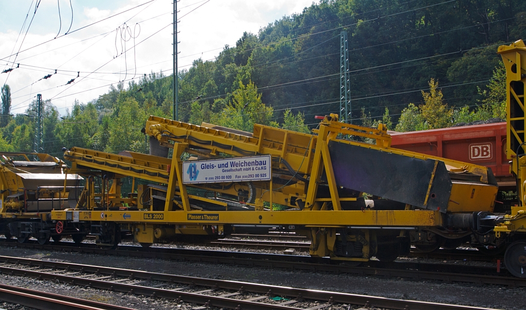 Plasser & Theurer Beladestation BLS 2000 gf (Schweres Nebenfahrzeug Nr. 97 19 26 903 57-8) der MGW Gleis- und Weichenbau (Berlin), abgestellt am 22.09.2012 in Betzdorf/Sieg.

Um Schttgter mittels Erdbaugerten (Bagger etc.) in MFS-Einheiten frdern zu knnen, ist die Beladestation entwickelt worden. Sie besteht aus Schottertrichter, eine festen breitem Kettenfrderband und hydraulisch ein- und ausfahrbarem bergabefrderband mit Schwenkeinrichtung fr die Arbeit im Gleisbogen. 

Die BLS 2000 ist ein zweiachsiges, gleisfahrbares Gert. 
Technische Daten:
Hersteller: Plasser & Theurer
Fabriknummer: 4063
Baujahr: 2003
Das Eigengewicht: 28 t
Hhe: 	3.300 mm
Breite: 3.050 mm
Achszahl: 2
Lnge ber Puffer: 14.740 mm (Mit Schottertichter und agefahrenem Frderband entspr. lnger)
Hchstgeschwindigkeit im Zugverband: 	100 km/h
Minimal befahrbarer Kurvenradius: 120 m
Die Energie fr die Hydraulik liefert ein Dieselmotor, u.a. weden die Frderbnder hydraulisch angetrieben. 
Zur leichten Beladung kann der Schottertrichter whrend der Arbeit hydraulisch abgesenkt werden. Die Beladung kann auch durch Bagger oder Radlader erfolgen.