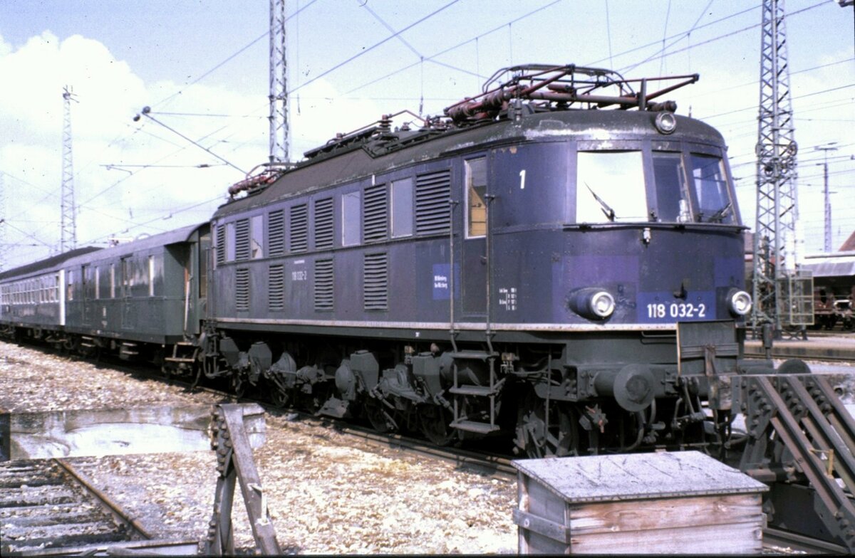 118 032-2 abgestellt mit Nahverkehrszug; der erste Wagen ist ein Packwagen Typ Düe 938 und Silberlinge, in Nördlingen am 07.03.1982.