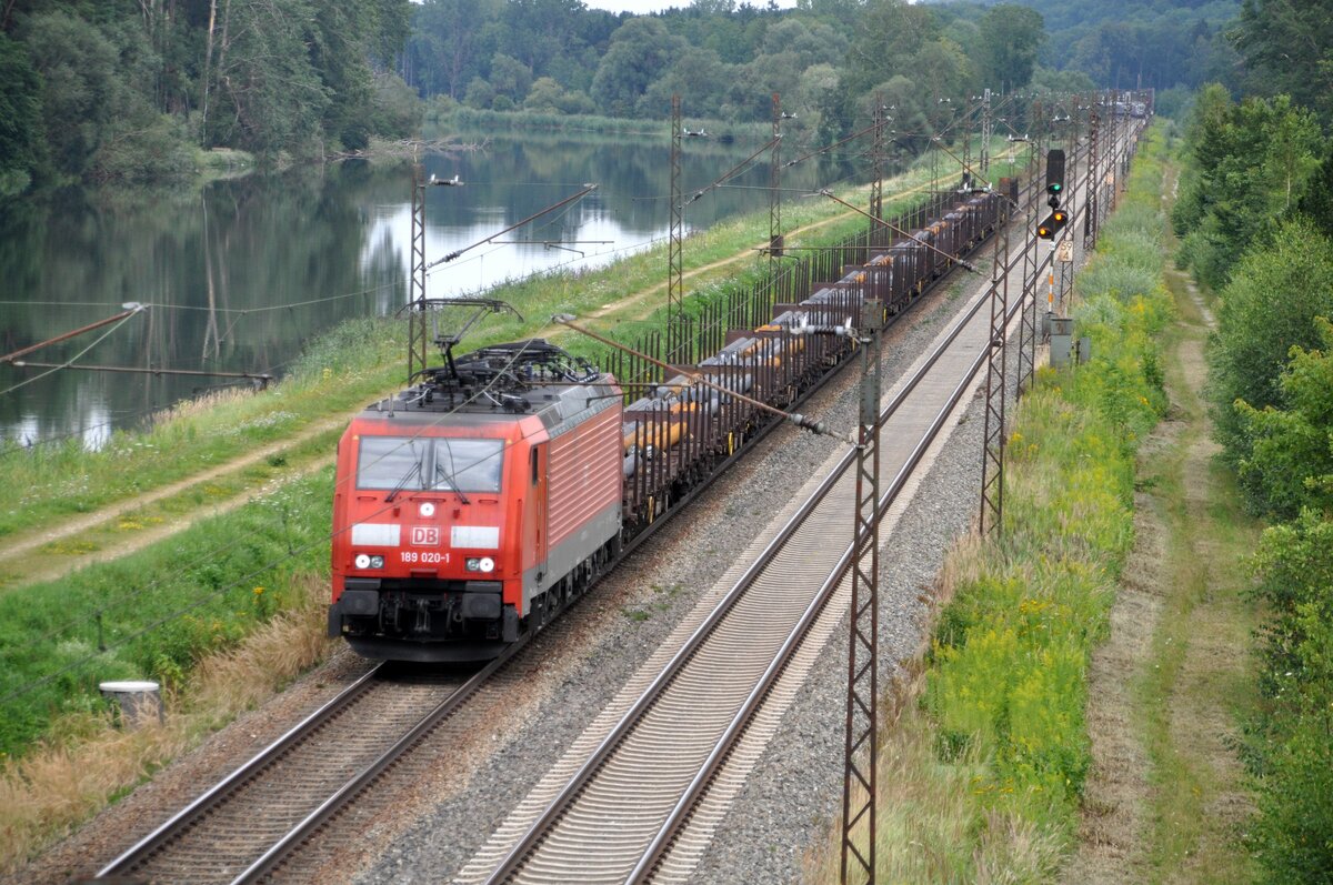 189 020-1 mit Rungenwagen beladen mit Stahlstäben; im Hintergrund entfernt sich ein ICE 1, in Günzburg/Reisensburg am 02.08.2017.