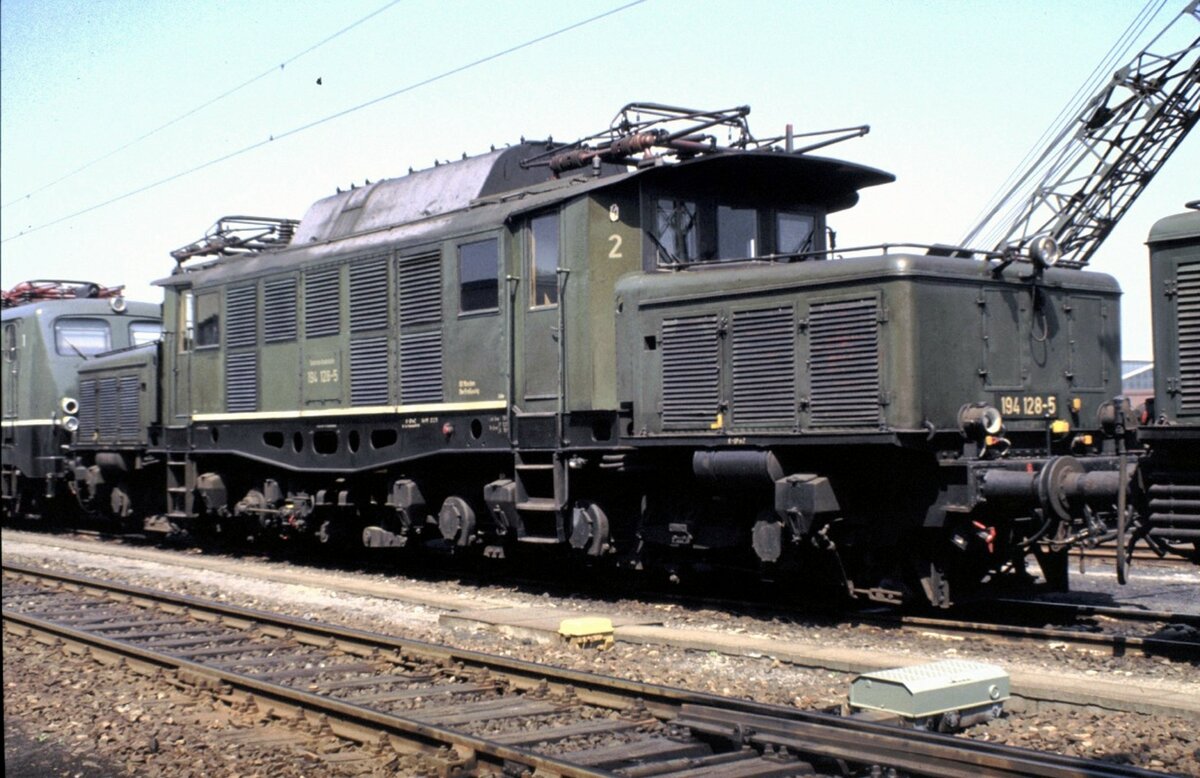 194 128-5 bei einer Führung in Regensburg am 15.05.1982. Der weiße Streifen am mittleren Kasten unten signalisiert: Diese Lok ist für max. 100 km/h zugelassen; ansonsten liegt die Geschwindigkeit für 194 bei 90 km/h.