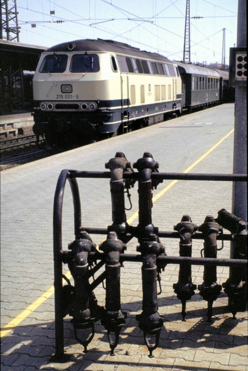 215 001-9 mit Eilzug; der erste Wagen ist ein Typ E 30 Wagen. Im Vordergrund ist ein Gestell für Heizungsschläuche in Ulm am 09.09.1982. In Ulm sind Anfang der 80er Jahre noch viele Wgen mit Dampfheizung im Einsatz.