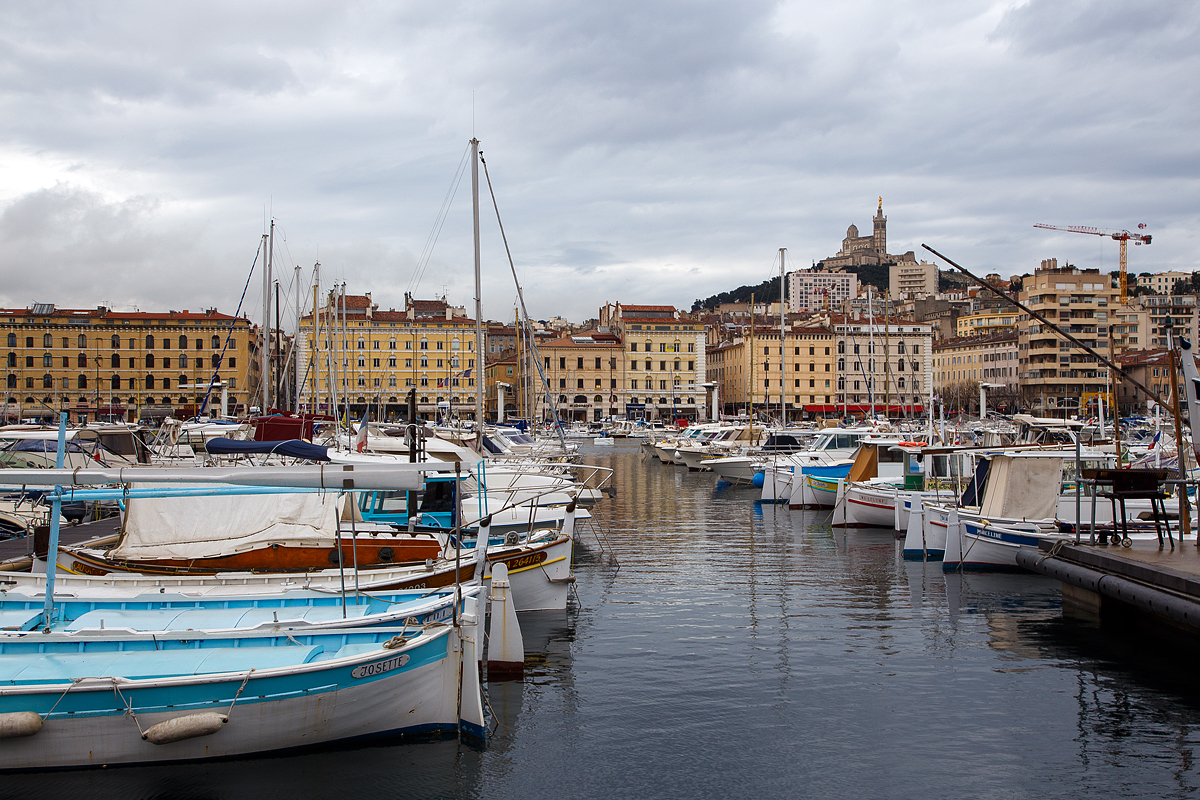 Alter Hafen von Marseille (le Vieux-Port de Marseille) am 25.03.2015 mit Blick (oben) auf die Wallfahrtkirche Notre-Dame de la Garde (im Volksmund La Bonne Mère – „die gute Mutter“). 

Der Hafen entstand in der Antike. Er ist das historische und kulturelle Zentrum von Marseille und war bis Mitte des 19. Jahrhunderts auch sein wirtschaftliches Zentrum für den Seehandel im Mittelmeer und für den Handel mit den französischen Kolonien. Das Hafengewerbe verlagerte sich dann allmählich nach Norden zum jetzigen Marseille Europort. Heute ist der Alte Hafen ein Yachthafen, ein beliebter Versammlungsort und das touristische Wahrzeichen der Stadt. Von ihm fahren aber auch die Fähren zu den Frioul Inseln (Chateau d' If und Port Frioul). Auch einige Fischerboote ankern noch hier, täglich findet am Morgen am Quai de la Fraternité ein Fischmarkt statt. 
