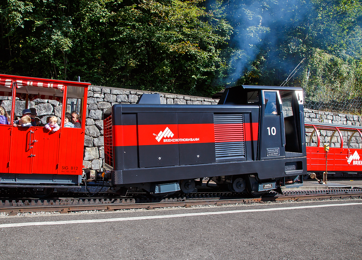 Auch eine Diesellok raucht....
Die Dieselhydraulische Hm 2/2 Zahnradlokomotive BRB 10 muss am 25.09.2016 als Verstärkung fahren. Bei wunderschönem Kaiserwetter, hatte es einen sehr großen Besucherandrang. Gleich drei vollbesetzte Züge fuhren um 10:50 Uhr hintereinander zum Brienzer Rothorn hinauf.

Brienz-Rothorn-Bahn (BRB) besitzt insgesamt drei solcher ganz spezieller Lokomotiven. Die Dieselhydrostatische Lok nach dem System Bernhard (Ingenieur Karl Bernhard) wurde 1975 von der Ferdinand Steck Maschinenfabrik AG in Bowil (CH) gebaut, der 600 PS starke Dieselmotor ist von der MTU. Im Jahr 2015 wurde die Lok von Steck in Bowil total revidiert.

Die werden vor allen im Bahndienst, z.B. für Materialtransporte fürs Hotel oder für Umbauten, eingesetzt. Eine Lok wird immer als 'Entpannungs-' und Feuerwehrlok als Ersteinsatzelement in Brienz verfügbar gehalten. Bei wirklich großem Andrang (wie an diesem Tage) oder bei technischen Ausfällen, kann auch eine dieser Loks zum Personentransport eingesetzt werden.

TECHNISCHE DATEN:
Spurweite: 800 mm
Zahnstangensystem:  Abt
Achsfolge: 2zz (d.h. 2 nicht angetriebene Tragachsen, 2 Triebzahnräder)
Triebzahnraddurchmesser: 573 mm 
Tragraddurchmesser: 653 mm 
Motorleistung: 485 kW / 660 PS

Kraftübertragung:
Antriebsleistung durch Dieselmotor, über Verteilergetriebe werden zwei Axialkolbenpumpen (Hydraulikpumpen) angetrieben. Das Ölfördervolumen und -Richtung werden durch zwei Proportionalventile gesteuert und speisen zwei parallel geschalteten Konstanthydraulikmotoren, die die Kraft über ein Übersetzungsgetriebe auf die Zahnräder bringen. Somit ist dies ein ganz anders Antriebs Prinzip als bei einer Adhäsions-Diesellokomotive.
Bremsenergie hydraulisch über Bremsventil gedrosselt, nebst hydrostatischer Betriebsbremse noch zwei weitere, voneinander unabhängige Bremssysteme

Tankinhalt: 450 Liter (Dieselöl)
Verbrauch: 66 Liter Dieselöl-Bedarf pro Fahrt Brienz-Rothorn und retour
Zugkraft: 80 kN 
Höchstgeschwindigkeit: 14,0 km/h bei Bergfahrt, 250 ‰ und unter Volllast
Höchstgeschwindigkeit: 12,0 km/h Höchstgeschwindigkeit bei Talfahrt, 250 ‰ und unter Volllast

Länge über Puffer: 5.250 mm 
Breite: 2.100 mm 
Höhe: 3.200 mm H
Dienstgewicht: 13.200 kg 
    
Beschaffungskosten (1975):    450.000
Beschaffungskosten (1987-Lok 11): 1.000.00000 CHF 

