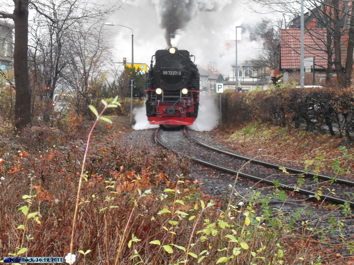 Bei Regenwetter dampft 99 7237-3 am 16.12.2011 mit dem Personenzug nach Eisfelder Talmhle gerade durch Wernigerode. In wenigen Sekunden wird der Zug ber den Bahnbergang nach der Westerntorkreuzung fahren.