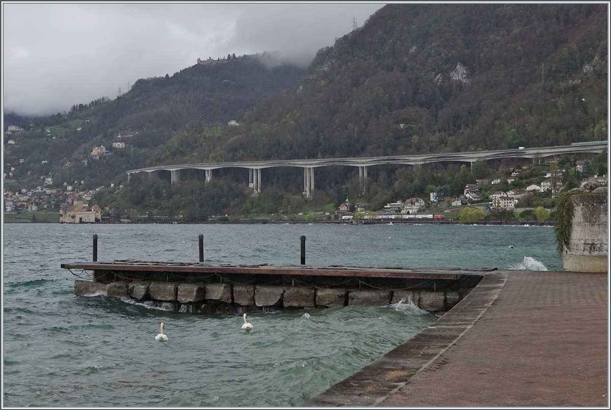 Beim Blick über den aufgewühlten Genfersee ist weit im Hintergrund recht des Château de Chillon eine SBB Re 460 mit ihrem IR90 auf der Fahrt nach Brig zu entdecken. 

1. April 2024