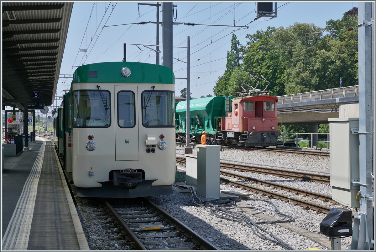 Der BAM MBC Te III 147 schiebt in Morges die normalspurigen Kieswagen auf die Rollbockanlage, während links im Bild eine BAM MBC Regionalzug auf die Abfahrt nach Bière wartet. 

19. Juli 2021