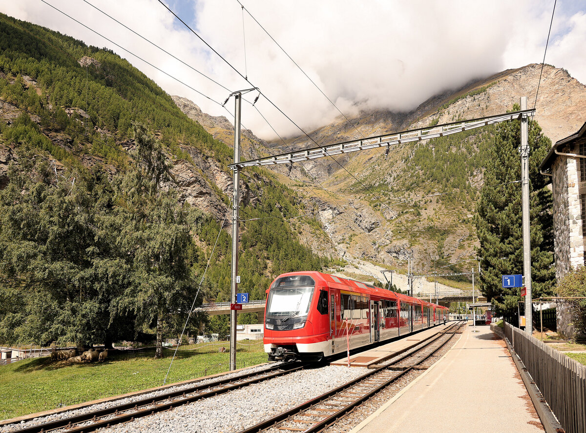 Der Bergsturz von Randa (korrekte Aussprache: Randaa). Drei schwere Bergstürze ereigneten sich 18.April, 21.April und 9.Mai 1991 kurz unterhalb Randa, wobei die Bahnlinie schon am 18.April zerstört wurde. Der horrende Bergsturz vom 9.Mai verschüttete auch einen Weiler und verursachte eine riesige Staubwolke. Juni/Juli folgten dann schwere Zerstörungen und Ueberschwemmungen nach Stürmen. Erstaunlicherweise konnte der Bahnbetrieb schon am 10.August 1991 definitiv wieder aufgenommen, nachdem eine komplett neue, 2860 m lange Strecke gebaut worden war. Diese weist nicht nur eine steile Zahnstangenstrecke (tal-)aufwärts auf, sondern nach dem Scheitelpunkt der neuen Strecke dann auch eine Zahnstangen-Steilrampe wieder abwärts bis zum Bahnhof Randa. Im Bild die beiden  Orion  Triebzüge ABeh8/12 308 und 302. Oben rechts sieht man die Abbruchstelle, von wo die Gesteinsmassen zu Tal donnerten. 30.August 2025 