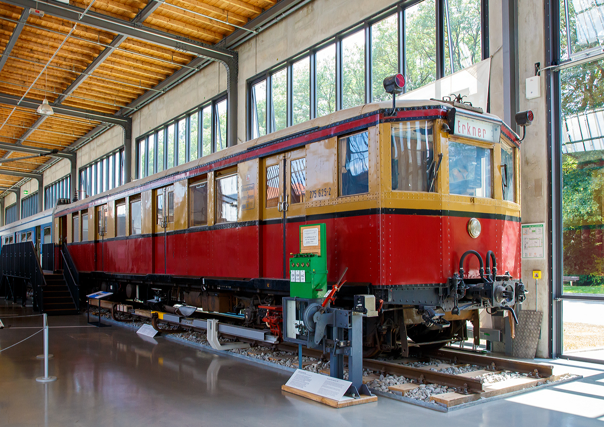 
Der ehemalige Berliner S-Bahn Triebwagen 275 625-2 (einer von vier Prototypen der Bauart Stadtbahn), ausgestellt im Verkehrszentrum des Deutschen Museums in München (Theresienhöhe), hier am 16.06.2018. Seit 2006 Leihgabe vom Verein Historische S-Bahn e.V., Berlin.

Der Triebwagen wurde 1927 von der WUMAG (Waggonbau Görlitz) gebaut.

Der Wagen hat die folgenden Fahrzeugnummern getragen:
1927 bis 1930 DRG elT 2187
1930 bis 1941 DRG (ab 1937 DR) elT 3110
1941  bis 1970 DR ET 165 040
1970 bis 1991 DR 275 625-2
1992 bis 1993 DR 475 161-6, war jedoch nie angeschrieben, da dieses bereits vorher abgestellt war. Umzeichnung erfolgte nur buchmäßig.

Als am 8. August 1924 der elektrische Betrieb auf der Vortortstrecke Bernau und im Folgejahr nach Oranienburg begann, suchte die Deutsche Reichsbahn-Gesellschaft (DRG) nach einem geeigneten Fahrzeugtyp für die geplante „Große Elektrisierung der Stadt-, Ring- und Vorortbahnen . Die Versuchszüge und die Bauart Bernau erwiesen sich schnell als wenig geeignet. Erst die Bauart Oranienburg brachte den Durchbruch: gleichlange Trieb- und Beiwagen, alle Achsen des Triebwagens waren angetrieben. Aus den vierzehn Herstellerfirmen wählte die DRG sechs aus, welche als Lieferkartell die Großserie fertigen sollte, die eine Weiterentwicklung der Bauart Oranienburg darstellte: leichtere Wagenkästen, bessere elektrische Ausrüstung. Der Probezug traf 1927 in Berlin ein, im selben Jahr begann die Serienfertigung. Bis 1931 wurden insgesamt 1276 Wagen geliefert. Bis heute ein Rekord! Die Wagen kamen von den Firmen in das neu errichtete Reichsbahnausbesserungswerk Berlin-Schöneweide und wurden dort von den Elektrofirmen AEG und Siemens (als Lieferantenkartell unter dem Namen Wasseg zusammengeschlossen) sowie Bergmann Electricitäts-Werke (BEW) und Maffei-Schwarzkopf-Werke (MSW), ebenfalls eine Liefergemeinschaft, ausgerüstet.

Mit den neuen Fahrzeugen begann am 6. Juni 1928 der elektrische Betrieb auf der Strecke Potsdam—Erkner, der ersten im Rahmen der Großen Elektrisierung. In den folgenden Jahrzehnten bildeten diese Fahrzeuge das Rückgrat der Berliner S-Bahn und wurden mehrfach modernisiert. So fuhren die Stadtbahner in Form der Baureihe 476/876 noch bis ins Jahr 2000 durch Berlin und das Umland. Diese Einsatzzeit von über 70 Jahren ist absolut untypisch für ein Schienenfahrzeug und war auch der besonderen politischen Situation in und um Berlin geschuldet.

Der Viertelzug 275 625/626 trug bei Auslieferung die Wagennummern 2187 (Triebwagen) und 5205 (Beiwagen) und gehörte damit zu einen von vier im Jahr 1927 gebauten Prototypen. Bei Auslieferung trugen der Viertelzug eine ungewöhnliche Farbgebung, da die dritte Wagenklasse komplett gelb und die zweite rot lackiert war. Während die anderen drei Prototypen verschrottet bzw. in U-Bahn-Wagen umgebaut wurde, blieb 275 625/626 erhalten und ging in die Sammlung des Vereins über.

TECHNISCHE DATEN:
Bauart : Stadtbahn
Baujahr: 1927 (Prototyp)
Spurweite:  1435 mm (Normalspur)
Achsformel: Bo'Bo'
Länge über Kupplung : 35.460 mm
Drehzapfenabstand: 11.800 mm
Drehgestellachsstand:  2.500 mm
Antriebsleistung:  360 kW (4 x GBM 700)
Höchstgeschwindigkeit: 80 km/h
Gewicht: 38 t
Zustand: 70er und 80er Jahre
Stromsystem: 750 V Gleichspannung