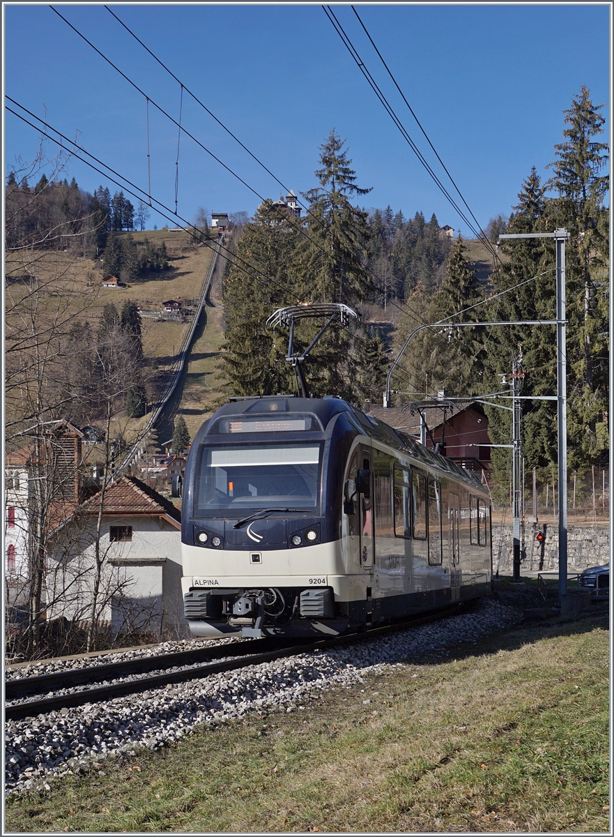 Der MOB Be 4/4 9204  Alpina  ist bie Les Avants mit einem Regionalzug auf dem Weg von Montreux nach Zweisimmen. Im Hintergrund links im Bild ist die Trasse der Standseilbahn Les Avant Sonloup zu erkennen. 

28. Jan. 2024