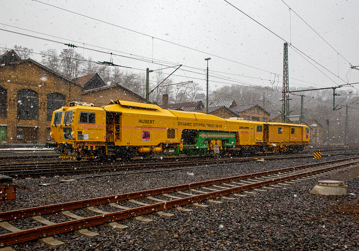 Der nächste Schneeschauer ist da und....
Der Plasser & Theurer Dynamic Stopfexpress 09-3X, Schweres Nebenfahrzeug Nr. 99 80 9121 026-5 D-JH, ex 97 40 71 507 17-1, eine Dreischwellenstopfmaschine Joseph Hubert GmbH & Co. KG, fährt am 06.04.2021 bei starkem Schneefall durch Betzdorf/Sieg in Richtung Siegen.


Der Dynamic Stopfexpress 09-3X wurde 2003 von Plasser & Theurer in Linz (A) unter der Maschinen-Nr. 3097 gebaut.  Die Dynamic 09-3X sind kontinuierlich arbeitende Nivellier-, Hebe-, Richt- und Drei-Schwellen-Stopfmaschinen mit integrierter dynamischer Gleisstabilisation. Sie ermöglichen das Stopfen von drei Schwellen in einem Arbeitsgang. Dadurch wird eine hohe Arbeitsgeschwindigkeit erzielt. Diese Maschinen sind jedoch für den Bereich von Weichen geeignet. Bei der Stopfung wird der Schotter unter der Schwelle verdichtet, wodurch ein stabiles Schwellenauflager entsteht.


TECHNISCHE DATEN:
Spurweite: 1.435 mm
Länge über Puffer: 33.540 mm
Gesamtgewicht: 126 t
Höchstgeschwindigkeit eigen/gezogen:100km/h 
Motorleistung: 550 kW

