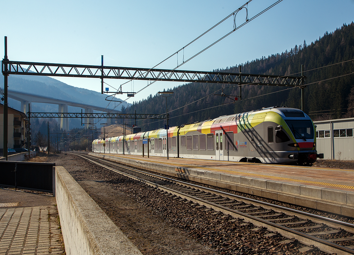 Der Trenitalia ETR 170 217, ein sechsteiliger Stadler FLIRT (MS für I / A) erreicht am 27.03.2022, als Regionalzug von Meran/Merano via Bozen/Bolzano nach Brenner/Brennero, den Bahnhof Gossensaß/Colle Isarco. 

Diese sechsteiligen Elektrotriebzüge vom Typ Stadler FLIRT wurden für den grenzüberschreitenden Verkehr zwischen Italien und Österreich konzipiert. Die 160 km/h schnellen Züge werden auf den Linien Meran-Bozen-Brenner, Unterland Trento-Ala und Franzensfeste-Innichen-Lienz (Pustertal) eingesetzt. Die aktuelle Flotte besteht derzeit aus 25 FLIRTs. Sie sollen auch noch im Vinschgau (Meran-Mals), unter 25 kV 50 Hz, eingesetzt werden. Sie sind mit dem Zugsicherungssystem ETCS ausgestattet. Der klimatisierte Innenraum und das offene und transparente Design machen die Reise mit angenehm für die Passagiere. Ein modernes Informationssystem versorgt die Fahrgäste mit allen notwendigen Informationen, sie sind zudem mit WLAN ausgestattet.

Im Hintergrund das Wipptal überbrückende Gossensaß-Viadukt (Viadotto Colle Isarco) der Brennerautobahn.