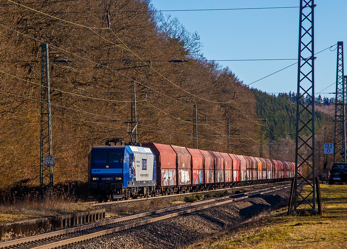 Die an die RBH Logistics vermietete 145 069-1 (91 80 6145 069-1 D-DB) der DB Cargo AG fährt am 01.03.2021, mit einem Schüttgutwagenzug (leere 4-achsige offene Schüttgutwagen mit schlagartiger Schwerkraftentladung der Gattung Falns 121), durch Dillbrecht an der Dillstrecke (KBS 445) in Richtung Siegen.

Die TRAXX F140 AC wurde 2000 von Adtranz in Kassel unter der Fabriknummer 33396 gebaut und an die DB geliefert, bis 2018 fuhr si für die DB Cargo und wurde dann an die RBH Logistics GmbH in Gladbeck vermietet und dort unter der internen Nummer RBH 228 geführt. 

Die RBH Logistics ist ein Tochterunternehmen der DB Cargo Deutschland AG und die Nachfolgegesellschaft von Werks-, Zechen- und Hafenbahnen im Raum der Bergwerksdirektion Recklinghausen. Durch die verschiedenen Firmenzusammenschlüsse und -aufteilungen ergab sich seit 1913 eine wechselvolle Geschichte. Das heute als Teil des Firmennamens genutzte Akronym RBH stand einige Jahre für die RAG-Bahn- und Hafenbetriebe und wurde beim Verkauf von dieser an die Railion Deutschland im Jahr 2005 beibehalten. Nach damaliger Angabe des neuen Eigentümers stehen die Buchstaben R, B und H nun für die Kernkompetenzen des Unternehmens: Eisenbahnverkehr (Rail), Binnenschifffahrt (Barge) und Hafenumschlag (Harbour).