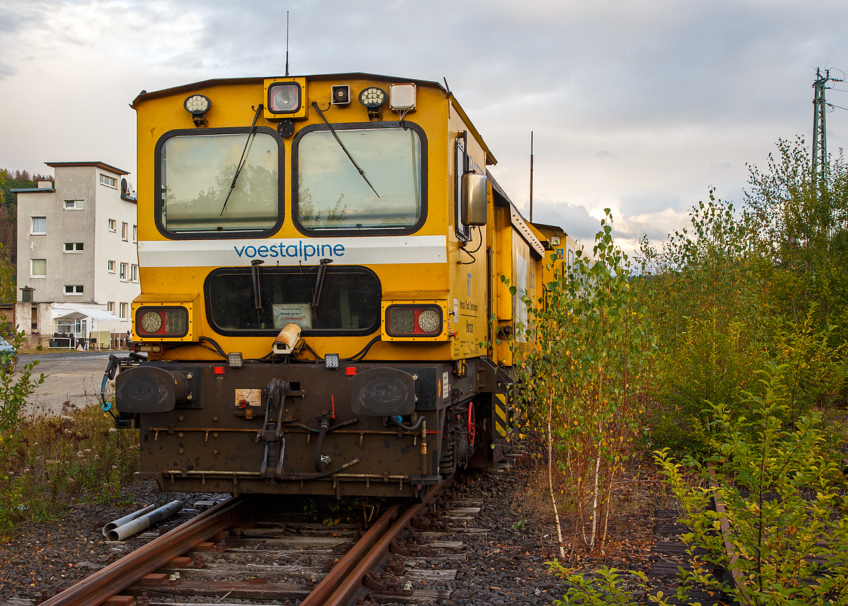 
Die Harsco Track Technologies Gleis- und Weichenschleifmaschine (engl. Rail Grinder) RGH 20 C „Facette“, Schweres Nebenfahrzeug Nr. 99 80 9127 001-2 D-VABWG, der voestalpine BWG GmbH aus Butzbach (Betreiber – EVU: Hessische Güterbahn GmbH) ist am 25.09.2020 in Betzdorf (Sieg) abgestellt, leider etwas im Gebüsch.

Der Schienenschleifzug wurde 2010 von der Harsco Track Technologies (HTT) in den USA unter den Fabriknummern 153635 und 153636gebaut. Das Fahrzeug hat die EBA-Nummer EBA 03C18A003.

Der Schienenschleifzug ist dreiteilig, an beiden Enden befinden sie die selbstfahrende 4-achsige (2 Drehgestelle) 10-Steine-Schienenschleifmaschinen (RGH 10C2-38 bzw. RGH 10C2-39) und dazwischen ein antriebsloser zweiachsiger Mittelwagen. Die selbstfahrende 20-Steine-Schienenschleifmaschine dient zur Beseitigung von Fahrflächenfehlern, Schäden aus Rollkontaktermüdung und der kohlenstoffarmen Randschicht aus dem Walzprozess sowie zur Schienenkopfprofilierung. Der Einsatz erfolgt vorwiegend in Weichen, Kreuzungen und Bahnübergängen ohne Demontage von Ausrüstungsteilen.
Jeder Schleifkopf bestehend aus einem Hydromotor, einer Spindel-Lager-Einheit und einer Schleifscheibe ist unabhängig gelagert und wird einzeln gesteuert, so dass bei 1 Überfahrt 10 verschiedene Facetten geschliffen werden können. Die Winkelstellung, seitliche Position und Sollstellung werden komplett in Schleifabläufen programmiert. 
Der Schleifdruck jeder Scheibe ist einzeln regelbar. Der zulässige Winkelbereich beträgt 75˚ auf der Schieneninnenseite bis 45˚ auf der Schienenaußenseite, gemessen zur Senkrechten. Zur Kontrolle des Ergebnisses ist ein Schienenprofilmesssystem vorhanden.

An beiden Schleifwagen ist eine Staubabsaug und-sammeleinrichtung vorhanden, die Absaugung erfolgt jeweils durch einen Ventilator, der einen Luftstrom von ca. 8.000 m³/h erzeugt. Beide Schleifwagen verfügen zudem über eine integrierte Feuerlöschanlage.

Technische Daten:
Spurweite: 1.435 mm
Achsfolge: Bo’Bo’ + 2 + Bo’Bo’
Anzahl der Achsen: 10
Länge über Puffer: 41.738 mm (13,94 / 13,85 / 13,94 m)
Breite: 2.629 mm
Höhe über SOK: 3.928 mm
Gesamtgewicht: 124 t
max. Achslast: 15 t (Zul. Streckenklasse A und höher)
Höchstgeschwindigkeit (Eigen / Schlepp): 100 km/h
Kleister befahrbarer Gleisbogen: R 90 m
Zur Mitfahrt zugel. Personen: 5
Max. Anhängelast: 50 t

Schleifspezifische Kennwerte:
Aufstelllänge vor Schleifbeginn: 60 m
Geräuschentwicklung (25 m Abstand): 73 dbA
Schleifgeschwindigkeit: 3 bis 8 km/h
Schleifrichtungen: 2 
Drehzahl der Schleifmotoren: 5.500-6.000 min-1
Leistung der Schleifmotoren: 17 kW
Schleifscheiben: Topfscheibe (16 Stück) Ø 152 mm und Tellerscheibe (4 Stück) Ø 280 mm
