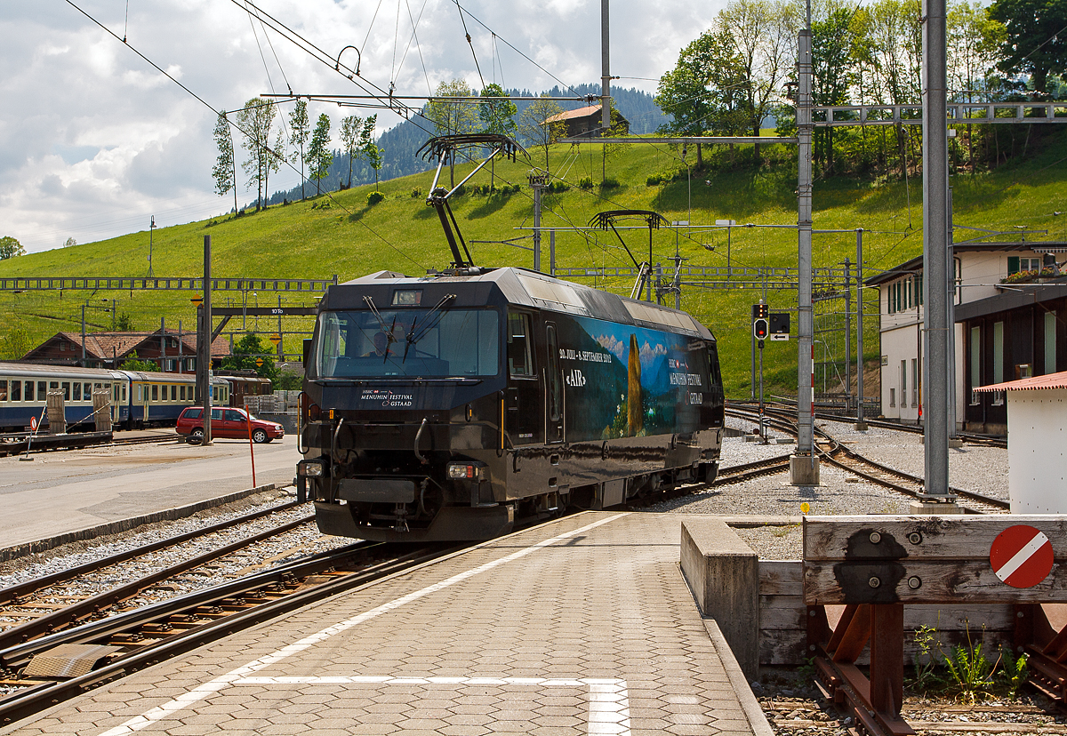 
Die MOB Ge 4/4 8003 (mit Werbung für das Menuhin-Festival 2012 „Air“ in Gstaad) am 28.05.2012 beim Manöver (Umsetzen) im Bahnhof Zweisimmen.

Die Lok wurde 1994 von der Schweizerische Lokomotiv- und Maschinenfabrik (SLM) in Winterthur gebaut, die elektrische Ausrüstung ist von ABB Verkehrssysteme AG. Die Lok wurde 2019 an die Rhätische Bahn (RhB) verkauft und wird dort zur Ge 4/4 653 umgebaut. Die GE 4/4 sind die leistungsstärksten schweizerischen Gleichstrom-Triebfahrzeuge. Die Maschinen der MOB (Montreux–Berner Oberland-Bahn) haben übrigens keine Eigennamen oder Wappen, sie tragen nur die Betriebsnummer.

Die vier 1994 von SLM und ABB für die MOB gebauten Ge 4/4 ähneln sowohl optisch als auch mechanisch den Ge 4/4 der Bière-Apples-Morges-Bahn (BAM) und den Ge 4/4 III der Rhätischen Bahn (RhB). Der elektrische Teil musste jedoch dem Betrieb ab Fahrleitung mit 900 V Gleichspannung angepasst werden und eine allfällige Umrüstung auf Zweisystem-Betrieb mit zusätzlich 15 kV 16,7 Hz berücksichtigen. Der Betrieb mit Wechselspannung wäre notwendig gewesen, wenn die GoldenPass-Linie mit einer dritten Schiene bis Interlaken verlängert worden wäre. So ist im Lokkasten bereits der Platz für einen Transformator für den Betrieb bei 15 kV mit 16 2/3 Hz Wechselstrom vorgesehen, ebenso lässt sich ein dritter Pantograph nachrüsten.

Die Lok ist mit vier Schnellschaltern ausgerüstet, die über Drosseln die wassergekühlten Stromrichter versorgen. Die Eingangsspannung der Wechselrichter kann von 630 bis 1080 Volt variieren, für den Zweispannungsbetrieb hätte die Zwischenkreisspannung 1350 Volt betragen. Dies erforderte eine Anpassung der Fahrmotorwicklung gegenüber den RhB-Loks, die für eine Zwischenkreisspannung von 2100 bis 2800 Volt ausgelegt sind. Der mechanische Teil des Fahrmotors ist baugleich mit demjenigen der RhB-Motoren.

Die Loks haben eine Leistung von 2000 kW und erreichen eine Höchstgeschwindigkeit von 120 km/h, die jedoch im Normalbetrieb mangels geeigneter Strecken nicht erreicht wird. Wegen der relativ geringen Spannung sind sehr hohe Stromstärken erforderlich. Daher fahren die Loks der Montreux–Berner Oberland-Bahn (MOB) immer mit zwei Stromabnehmern am Fahrdraht. Zudem sind die Stromabnehmer mit drei statt den üblichen zwei Schleifleisten versehen, was man hier im Bild auch gut sehen kann.

Möglich ist auch die Vielfachsteuerung mit den MOB GDe 4/4, was erst erforderlich ist, wenn mehr als sechs Panoramawagen zu befördern sind. Dies ist bisher nur vereinzelt vorgekommen.

Die Loks hatten (wie im Bild auch zu sehen) Mittelpuffer mit einer Schraubenkupplung, ab 2017 wurden die drei bei der MOB verbliebenen Loks auf automatische Mittelpufferkupplung (Schwab-Kupplung) umgebaut. Seit 2020 sind die verbliebenen 3 Lokomotiven mit allen Fahrzeugen Steuerwagen sowie den Triebwagen mit Schwab-Automatikkupplung in Vielfachsteuerung kompatibel und

TECHNISCHE DATEN:
Gebaute Anzahl: 4, die Ge 4/4 8003 wurde 2019 an die RhB verkauft. 
Hersteller mech. Teil: SLM, Winterthur 	  	
Elektr. Ausrüstung: ABB Verkehrssysteme AG
Spurweite: 1.000 mm (Schmalspur)
Achsfolge:	Bo'Bo'
Länge über Puffer: 16.100 mm 
Treibraddurchmesser: 	1.070 mm
Breite max.: 2.800 mm
Höhe : 3.860 mm 	  	
Dienstgewicht: 63 t
Anzahl der Fahrmotoren:  4
Maximale Leistung am Rad:	2.400 kW 	 
Dauerleistung am Rad: 2.000 kW 	  	 
Dauerzugkraft am Rad: 150 kN
Anfahrzugkraft am Rad:  200 kN
Höchstgeschwindigkeit: 120 km/h 	  
Anhängelast bei 45 km/h und 73‰ Steigung: 170 t
Anhängelast bei 80 km/h und 25‰ Steigung:	300 t
Stromsystem: 900 V DC (Gleichstrom)
Stromübertragung: 2 Einholmstromabnehmer mit je 3 Schleifleisten
