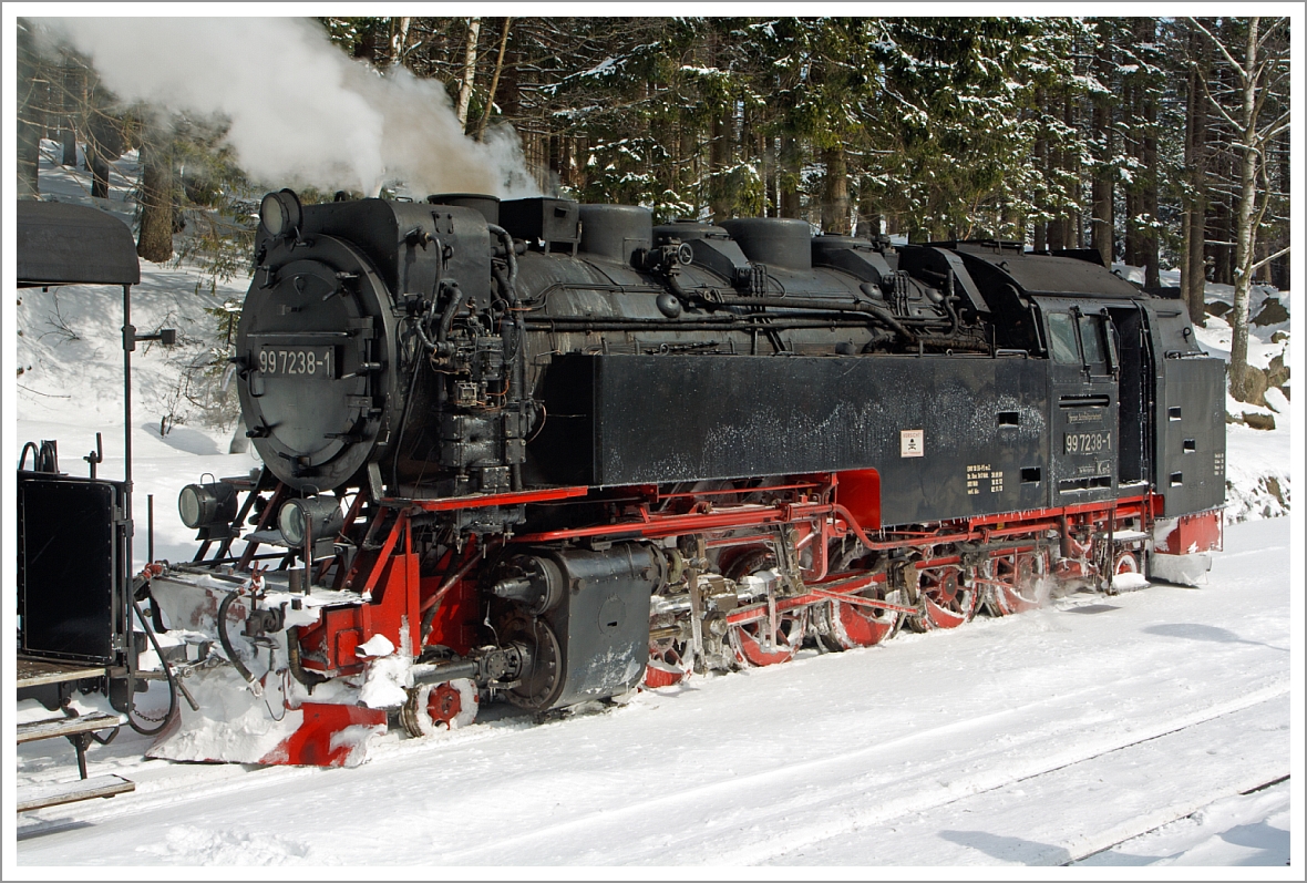 Die Neubaulokomotive 99 7238-1 der HSB (Harzer Schmalspurbahnen GmbH) hat am 23.03.2013 ihren Sonderzug vom Brocken zum Bahnhof Schierke hinab gebracht. 
Die Spuren von dem viele Schnee Mitte Mrz von auf dem Brocken sind (1,5 m) deutlich zu sehen.

Die Neubaumaschinen 99 231 bis 99 247 wurden in den 50er Jahren fr die Schmalspurbahnen Eisfeld - Schnbrunn, Gera-Pforten - Wuitz - Mumsdorf und die Harzquer- und Brockenbahn durch den VEB Lokomotivbau  Karl Marx  in Babelsberg gebaut. Dies war unbedingt ntig, da der Lokomotivpark dieser Bahnen vllig beraltert war. Auerdem ging ein Teil der Maschinen im Krieg verloren. 

Die Konstruktion der Neubaumaschinen lehnt sich sehr stark an die der Einheitslokomotiven 99 221 bis 99 223 an. Von diesen ist aber nur die 99 222 erhalten geblieben. In vielen Konstruktionsmerkmalen weicht die Neubaulok jedoch von ihren Vorbildern ab. So wurde zum Beispiel der Rahmen als Blechrahmen ausgefhrt. Die technologischen Mglichkeiten der Nachkriegszeit lieen die Ausfhrung als Barrenrahmen nicht zu. Der Kessel ist vollstndig geschweit, wobei der Langkessel aus einem einzigem Kesselschuss besteht. 
Nach der Einstellung des Betriebes auf der Eisfeld   Schnbrunner Strecke gelangten auch die 99 231, 99 235, 99 236 und 99 237 in den Harz. In einigen Details mussten diese Maschinen verndert werden. Der Grund hierfr besteht in den engen Bgen der Harzstrecken. Die Einheitslokomotiven  99 222 kam bereits 1966 in den Harz.

Anfang der 70er Jahre erfolgte eine Umnummerierung der Lokomotiven. Aus der 99 231 wurde die 99 7231 usw.. Dies sollte sich zwischenzeitlich noch einmal ndern, als Ende der 70er Jahre alle Neubaumaschinen auf lhauptfeuerung umgestellt wurden. Nun wurde aus der 99 7231 die 99 0231 usw.. Dies war fr diese Lokomotiven eine nicht besonders positive Manahme. Bei dem Umbau glaubte man, Brennstoff-Einsparungen vornehmen zu knnen. Die Einsparung eines zweiten Brenners erkaufte man sich aber mit Kesselschden. 

Im Rahmen der lablsung in der damaligen DDR baute man die Maschinen wieder auf Rostfeuerung um. Ein Segen fr die Loks aber auch fr die Umwelt, denn nicht verbranntes l sickerte nicht mehr in die Gleise und in den Boden. 
Heute ist die Arbeit des Heizers zwar etwas beschwerlicher aber besonders in den Sommermonaten ist die Hitze lange nicht so gro wie damals mit dem geheizten ltender und dem harten lfeuer. 

Nun haben die Maschinen wieder ihre 99 72er Nummer. Obwohl die Deutschen Reichsbahn dazu berging Schmalspurdampflokomotiven mit 099 zu bezeichnen und mit einer neuen Betriebsnummer zu versehen, wurde auf den Harzer Schmalspurbahnen die alte Reichsbahnbezeichnung beibehalten.

Technische Daten dieser Loks:
Hersteller: VEB Lokomotivbau  Karl Marx  in Babelsberg 
Baujahre: 1954 - 1956
Achsfolge: 1'E1' 
Gattung: K57.10 
Spurweite: 1.000 mm (Meterspur) 
Lnge ber Puffer: 12.500 mm
Kesselberdruck : 14 bar
Leistung: 515 kW (700 PS)
Hchstgeschwindigkeit: 40 km/h (Vor- und Rckwrts)
Dienstgewicht: 64,5 t (bei vollen Vorrten)
Kohlevorrat: 4,0 t
Wasservorrat: 8 m
Achslast: 9,5 t
