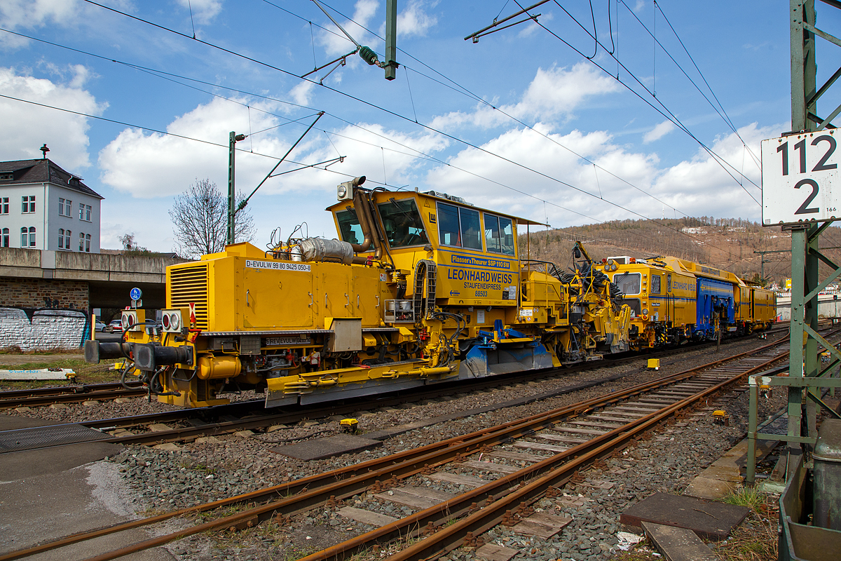 Die Plasser & Theurer Universalstopfmaschine UNIMAT 09-4x4/4S (Kombinierte Gleis- und Weichenstopfmaschine), Schweres Nebenfahrzeug Nr. D-EVULW 99 80 9424 022-1 „Stuifenexpress“  588627, und die Plasser & Theurer Schnellschotterplaniermaschine SSP 110 SW, Schweres Nebenfahrzeug Nr. D-EVULW 99 80 9425 050-8 „Staufenexpress“ 88503, ex 97 16 40 574 17-6, beide von der Leonhard Weiss GmbH & Co. KG (Göppingen) fahren am 09.04.2021 als Zugverband durch Niederschelden in Richtung Siegen. Hier passieren sie gerade den Bü 343 (Km 112,183 der Siegstrecke KBS 460).

Die Stopfmaschine UNIMAT 09-4x4/4S wurde 2017 von Plasser & Theurer unter der Maschinen-Nr, 6559 gebaut. Der Schotterpflug SSP 110 SW wurde 2002 von  Plasser & Theurer unter der Maschinen-Nr,   716 gebaut.