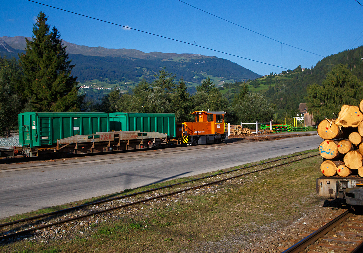 Die RhB Tm 2/2 119 (eine Schma CFL 250 DA) steht am 06.09.2021 beim Bahnhof Surava mit einem Gterzug abgestellt, vor der Lok der RhB Sl 7760 ACTS-Tragwagen mit 2 ACTS-Container. Aufgenommen aus einem Zug heraus.

Die Lok wurde 2004 von Schma (Christoph Schttler Maschinenfabrik GmbH) in Diepholz unter der Fabriknummer 5997 gebaut und an die RhB geliefert.

Als Tm 2/2 werden Verbrennungsmotor betriebene Traktoren (Kleinlokomotiven) bezeichnet, die Achsverhltnis 2/2 haben. Im Jahr 2001 /2002 beschaffte die RhB bei Schma die Traktoren (Dieselloks) Tm 2/2 111 bis 114. Hierbei handelt es sich um einen Nachbau der Serie Tmf 2/2 85-90, wobei man allerdings auf die (nur selten verwendete) Funkfernsteuerung verzichtete. Diese Traktoren besorgen den Rangierdienst auf greren Stationen. In den Jahren 2004 bis 2006 kamen weitere sechs Traktoren Tm 2/2 115–120 dazu.

TECHNISCHE DATEN (2. Serie):
Hersteller: Schma (Christoph Schttler Maschinenfabrik GmbH)
Baujahre: 2006 (2. Serie)
Gebaute Stckzahl: 6
Spurweite: 1.000 mm
Achsfolge: B
Lnge ber Puffer: 7.800 mm
Breite: 2.700 mm
Treibraddurchmesser: 750 mm
Leergewicht: 25 t
Hchstgeschwindigkeit: 60 km/h (60 km/h Schleppfahrt)
Motorbauart: 6-Zylinder-Dieselmotor, Typ Cummins KT-1150-L
Motorleistung: 336 kW
Anfahrzugkraft: 78 kN
Stundenzugkraft: 30 kN bei 25 km/h
Leistungsbertragung: hydraulisch

Der RhB Sl 7760 ACTS-Tragwagen mit 2 ACTS-Container.

Die Bndner Gterbahn besitzt eine groe Flotte an vierachsigen ACTS-Bahnwagen mit einem Traggewicht zwischen 33 und 46,5 Tonnen. Jeder ACTS-Bahnwagen kann mit ein oder zwei ACTS-Containern beladen und auf dem Schienennetz der Bndner Gterbahn transportiert werden. Das ideale Transportmittel fr Kies, Sand, Splitt, Bauschutt, Ausbruchmaterial, Altpapier, Altglas, Alteisen, Kehricht (gepresst oder lose), Kehrichtschlacke, Klrschlamm, Holzschnitzeln, Wuhrsteine und vielem mehr.

TECHNISCHE DATEN:
Typenbezeichnung:  SL (7751 – 7771)
Inbetriebnahme:  2000/2001
Spurweite: 1.000 mm
Anzahl der Achsen: 4
Lnge ber Puffer: 16.040 mm 
Drehzapfenabstand: 11.000 mm 
Raddurchmesser (neu): 690 mm
Ladelnge: 15.000 mm
Ladebreite: 2.660 mm
Hhe ab Schienenoberkante: 860 mm
Eigengewicht: 16 t 
Ladegewicht:  4