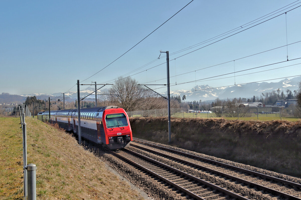 Die Strecke Uster - Wetzikon - Rüti ZH - Rapperswil: Ein Zug der S15 in Bubikon, mit Blick auf die Alpen. Die S15 fährt von Rappersil aus über Wetzikon, Uster, Zürich Stadelhofen, Zürich Hbf. weiter nach Nordwesten nach Oberglatt und Niederweningen. Uebrigens dürfte dieser Abschnitt Oberglatt-Niederweningen eine der letzten dampfbetriebenen SBB-Strecken gewesen sein. 5.März 2025 