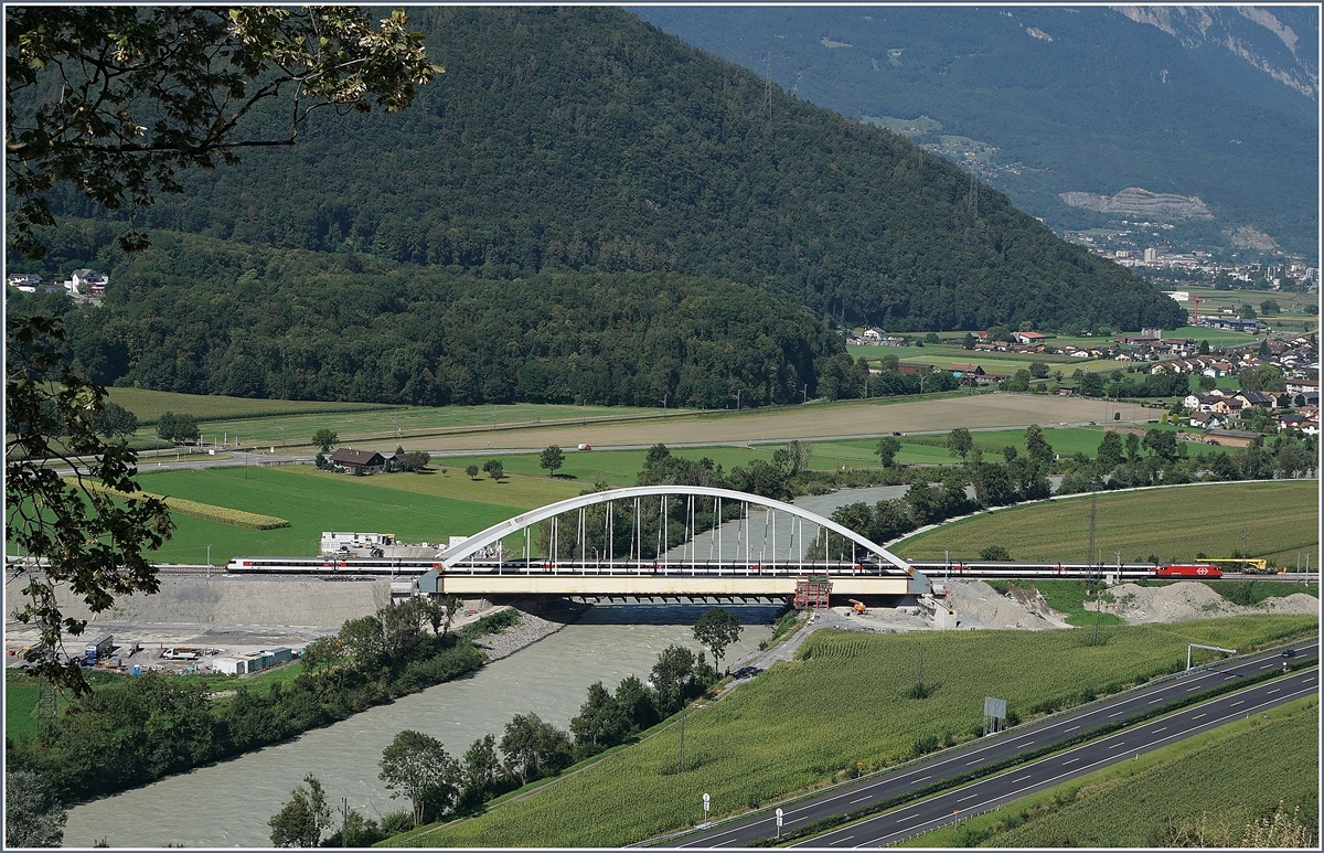 Die Suche nach einem besseren Fotostelle fr die neue Rhonebrcke fhrten mich an Nahe an den sicheren Abgrund; doch von dort hat man eine schnen Blick auf die Brcke und die Rhone-Eben des Chablais. Im Hinterrund ist Monthey zu erkennen, in der Bildmitte liegt Massongex und auch die Fahrplanfeld Strecke 130 (St-Maurice - St-Gingolph) ist zu sehen. Das Gebiet rechts der Rohne gehrt bereits zum Kanton Waadt, welches eine Re 460 mit dem IR 1816 von Brig nach Genve gerade erreicht hat. 26. August 2016