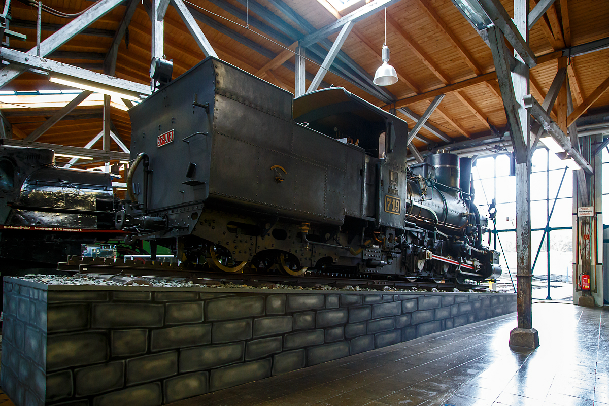 Die Zahnraddampflokomotive ex BHStB (Bosnisch-Herzegowinischen Staatsbahnen) / BHLB (Bosnisch-Herzegowinische Landesbahnen) IIIc5 719, ab 1918 SHS 719 (Železnice Kraljevine Srba, Hrvata i Slovenaca, deutsch Eisenbahnen des Königreichs der Serben, Kroaten und Slowenen, ab 1929 JDŽ 97-019 (Jugoslovenske Državne Železnice) und ab 1954 JŽ 97-019 (Jugoslovenske Železnice) am 11.09.2022 in der Lokwelt Freilassing.

Die Lok wurde 1908 von der Wiener Lokomotivfabrik Floridsdorf (WLF) für die Bosnisch-Herzegowinischen Staatsbahnen. Die WLF besaß die Lizenz des Zahnradbahn-Systems Abt für das Gebiet der damaligen Österreichisch-Ungarischen Monarchie. Die Außerdienststellung der Lok erfolgte erst Mitte der 1970er Jahre. Die Lok ist Eigentum vom Deutschen Museum – Verkehrszentrum.

Die österreichisch-ungarische Verwaltung erbaute nach der militärischen Okkupation der Provinz Bosnien-Herzegowina des osmanischen Reiches ein umfangreiches Schmalspurnetz mit der Spurweite von 760 mm. Bis 1908 agierte dieses Bahnnetz unter den Namen Bosnisch-Herzegowinische Staatsbahnen (BHStB), ab 1908 als „Bosnisch-Herzegowinische Landesbahnen (BHLB).

Die Zahnraddampflokomotiven der Reihe IIIc5 701–721 waren Stütztenderlokomotiven mit drei Kuppelachsen für Adhäsions- und Zahnradantrieb in Bosnischer Spurweite, beschafft von den Bosnisch-Herzegowinischen Staatsbahnen (BHStB). Der Zahnradantrieb (eigener zweizylindriger Antrieb) im System Abt (2 Lamellen) erfolgte durch zwei Zahnräder (Ø 688 mm). Die Nachfolgerinnen der BHStB, die Bosnisch-Herzegowinischen Landesbahnen (BHLB) und die Eisenbahnen des Königreichs Serbien, Kroatien und Slowenien (SHS) stellten weitere 17 Maschinen der Baureihe in Dienst. Bei den Jugoslawischen Eisenbahnen (JDŽ, später JŽ) wurde die Serie als Baureihe 97 bezeichnet. Sie ist mit 38 Exemplaren die in größter Stückzahl gebaute Zahnradlokomotive der Welt.

Die Reihe IIIc5 ist als Weiterentwicklung der IIIb4 konstruktiv stark an ihre Vorgängerin angelehnt. Die schmale Bosnische Spurweite machte bei beiden Typen die Verwendung eines Außenrahmens notwendig, in dem die drei gekuppelten Treibachsen gelagert sind. Wie bei den von der Lokomotivfabrik Floridsdorf stammenden Zahnradlokomotiven üblich ist der Zahnradantrieb als Innentriebwerk innerhalb des Lokomotivrahmens ausgebildet. Sowohl die außenliegende Steuerung für den Adhäsionsantrieb als auch diejenige für den Zahnradantrieb waren nach dem System Joy ausgeführt.

Für eine gefahrlose Talfahrt stehen fünf voneinander unabhängigen Bremssysteme zur Verfügung:
• Eine auf die zweite und dritte Adhäsionssachse wirkende mechanische Bremse, die mit Handkurbel und Spindel im Führerstand angezogen wird
• Auf die Zahnradachsen wirkende Bandbremsen, die auch mit Handkurbel und Spindel vom Führerstand aus bedient werden
• Die Gegendruckbremse des Adhäsionstriebwerks
• Gegendruckbremse der Zahnradantriebs, die zusammen mit der Gegendruckbremse des Adhäsionsantriebs als verschleißfreie 
• Die auf den Stütztender und die angehängten Wagen wirkende Vakuumbremse. 

Die Loks sind für den Betrieb mit einer zweilamelligen Zahnstange der Bauart Abt ausgerüstet. Der Zahnradantrieb der 2 Zahnräder verfügt über einen eigenen zweizylindrigen Antrieb, welcher unter der Rauchkammer, zwischen den beiden Zylindern des Adhäsionstriebwerks angebracht ist. Beide Triebwerke können getrennt von einander angesteuert werden.

Die Unterbringung der Wasser- und Kohlevorräte erfolgt in einem zweiachsigen „Stütztender“, der fest mit der Maschine gekoppelt ist und den hinteren Teil der Lokmotive trägt.

TECHNISCHE DATEN:
Gebaute Anzahl: 38
Hersteller:  Wiener Lokomotivfabrik Floridsdorf (WLF)
Baujahre:  1894–1919
Bauart: Czz2’t
Gattung: 33.8
Spurweite:  760 mm (Bosnische Spur)
Länge über Kupplung: 10.143 mm
Gesamtradstand: 6840 mm
Dienstgewicht: 36,5 bis 37,46 t (diese hier 36,8 t)
Höchstgeschwindigkeit: 30 km/h
Indizierte Leistung: 300 PS (ca. 220 kW)
Anfahrzugkraft:  80 kN
Kuppelraddurchmesser: 800 mm
Laufraddurchmesser: 650 mm
Zahnradsystem:  Abt (2 Lamellen)
Zahnraddurchmesser:  688 mm
Zylinderdurchmesser:  340 mm
Kolbenhub: 450 mm
Zylinderdurchmesser Zahnradantrieb: 360 mm
Kolbenhub Zahnradantrieb:  360 mm
Kesselüberdruck: 12 bar
Rostfläche: 1,58 bis 1,66 m²
Verdampfungsheizfläche: 89,0 m²
Tender: Stütztender
Wasservorrat: 3,5 m³
Brennstoffvorrat: 3,5 t

Die Nachbestellungen erfolgten ohne wesentliche Änderungen. Der Zahnradrahmen wurde durch höhere Barren verstärkt. Von der zweiten Lieferung an wurde die Rostfläche auf 1,58 m² verringert und die Radstände etwas verkleinert. Ab der dritten Teilserie wurde die Kühlwassermenge der Gegendruckbremsen von 0,4 auf 0,55 m³ erhöht. Die letzte Lieferung erhielt Abdampfvorwärmer Bauart Knorr. Durch die Änderungen veränderte sich das Gewicht. Bei den ersten Lokomotiven betrug das Leergewicht 27,2 t, bei der letzten Teilserie 29,09 t.