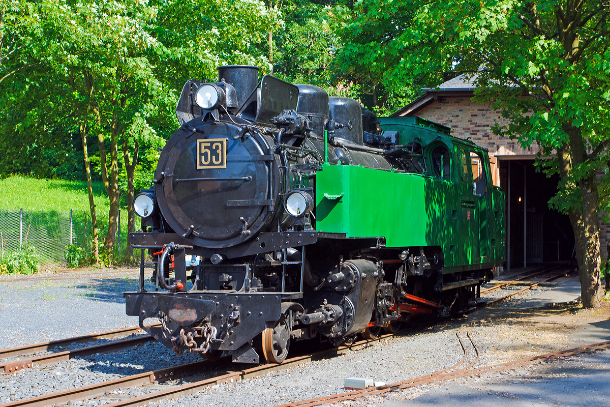 Ehemalige Schmalspur-Dampflokomotive Nr. 53 der Rhein-Sieg Eisenbahn (RSE) am 08.06.2014 im Museum Asbach (Ww). 

Bei dieser Tenderdampflokomotive handelt es sich um die größte, schwerste und leistungsfähigste ehemalige Lok der Rhein-Sieg Eisenbahn (RSE), gleichzeitig ist sie eine der modernsten Schmalspurdampfloks Deutschlands.

Die Lok wurde 1944 unter Fabriknummer 10175 von der Firma Jung in Jungenthal bei Kirchen/Sieg gebaut. 

Technische Daten:
Hersteller:  Lokomotivfabrik Jung/Jungenthal bei Kirchen/Sieg
Fabriknummer:  10175
Baujahr: 1944
Spurweite: 785 mm
Bauart:  1'D1' h2t
Baujahr: 1944
Leergewicht: 40,5 Tonnen
Dienstgewicht: 51 Tonnen
Wasser: 4,6 m³
Kohle: 2,0 Tonnen
Länge über Puffer: 11.345 mm
Breite:  2.260 mm
Höhe ü. SO:  3.370 mm
Höchstgeschwindigkeit: 50 km/h
max. Kesselüberdruck:  15 bar
Rostfläche:  2,0 m²

Ausrüstung:
Heusinger-Steuerung, Schieber Bauart Karl-Schulz, Antrieb auf 4. Kuppelachse, 1 und 4 Kuppelachse gebremst, 2. + 3. Kuppelachse um ± 25 mm seitenbeweglich; Nachlaufachse mit Außenrahmen und Zug- / Stoßeinrichtungen, Laufachsen als Bisselachsen, vorn ± 150 mm, hinten ± 200 mm; genieteter Kessel mit Stahlfeuerbüchse, Wagner-Heißdampfregler, genieteter Blechrahmen, 21,8 % ausgeglichene Massen, Strube Dampfstrahlpumpe (125 l/min), S.H.G. Abdampfstrahlpumpe (52/86 l/min), Einkammer-Druckluftbremse Bauart Knorr mit Zusatzbremse und Handhebelbremse, zweistufige Luftpumpe, Druckluftsandstreuer, Dampfheizung-Anschluß, Lichtmaschine

Geschichte:
Für den steigenden Basaltverkehr aus den Brüchen des Westerwalds zu den Reichsbahn-Übergabebahnhöfen Hennef und Siegburg und zum Rheinhafen in Beuel benötigte die RSE Ende der dreißiger Jahre neue Lokomotiven. Die C-Kuppler von Jung und O&K aus Zeit der Jahrhundertwende waren zu klein und veraltet, die drei Jung-D-Kuppler wurden für Rollwagenzüge benötigt, und die vier 1'D1'-Tenderloks aus den zwanziger Jahren (Jung und Borsig) reichten allein nicht aus.

So bestellte die Direktion 1939 bei der Lokfabrik Jung/Jungenthal zwei Neubaudampfloks, die den großen Verkehrsbedürfnissen entsprechend völlig neu konstruiert wurden und die Nummern 53 und 54 tragen sollten. Während der Zeit des zweiten Weltkriegs konnte eine solche Bestellung nur mit kriegswichtigen Transportgütern begründet werden, die sich bei der RSE in Form von Basalt für den Bau von Befestigungen und in U-Boot-Batterien der Bleihütte Luise (Krautscheid) fanden. Um die für den Bau benötigten Metallkontingente genehmigt zu bekommen, mußten erst einmal 60 Tonnen Schrott für 40 Tonnen Lokgewicht gesammelt werden. Die Kriegsereignisse behinderten den Bau so sehr, daß man zunächst nur eine Lok in Angriff nahm. Bereits 1943 erfolgte die Druckprobe des Kessels, aber die Fertigstellung der gesamten Lok verzögerte sich bis 1944. Am 12. Juni 1944 kam sie in Hennef an, aber erst am 31. Januar 1945 konnte die erfolgreiche Probefahrt nach Waldbröl und Asbach durchgeführt werden, die Abnahme erfolgte zwei Tage später.

Die 53 kam sofort in den Betriebsdienst und geriet während einer Fahrt durch das Bröltal im März '45 unter Tieffliegerbeschluß. Nur der Geistesgegenwart des Personals war zu verdanken, daß keine großen Schäden oder sogar Totalzerstörung eintraten. Die Einschußstellen sind noch heute sichtbar!

Nach Ende der Kampfhandlungen und langsamer Wiederaufnahme des Bahnbetriebs mit den üblichen Einschränkungen wurde die Lok bei ihrem Hersteller Jung repariert und kam mehr schlecht als recht wieder ans laufen. Die kriegsbedingte Verwendung minderwertiger Materialien zeigte nun Folgen, vor allem die stählerne Feuerbüchse bereitete viele Probleme. Die Jahre 1951 bis 1954 verbrachte sie im Herstellerwerk, erst nach Austausch der Feuerbüchse gegen eine solche aus Kupfer zeigte die 53 allgemein befriedigende Leistungen. Aber sie hatte Macken und war nicht leicht zu handhaben, weshalb nur ausgesuchte Lokführer mit ihr fahren durften, die sehr stolz auf ihre prächtige Maschine waren. 

1957 erfolgte in der Hennefer Werkstatt ein Umbau zum Betrieb mit Ölfeuerung, welche sich zuvor bei Lok 32 sehr bewährt hatte. Im Gegensatz zur DB, die für ihre später umgebauten Ölloks das zähe Bunkeröl C verwendete, benutzte die RSE das leichtere B-Öl. So entfiel die Notwendigkeit einer ständigen Ölheizung, mit der zähe Öle fließfähig gemacht werden müssen. Nun konnte auch der Heizer eingespart werden, die Bedienung des Kessels hatte der Lokführer mit zu verantworten. Bei Streckenfahrten fuhr nun der Zugführer zwecks Streckenbeobachtung im Führerstand mit, wodurch auch die Mitnahme des Packwagens entfallen konnte.

Zur noch rationelleren Betriebsdurchführung beschaffte die RSE 1959/60 drei Dieselloks vom O&K-Typ MV8 mit je 130 PS Leistung. Die anfällige 53 kam immer seltener zum Einsatz, ihre letzte Fahrt ist für den 17.8.1966 verbürgt. Zuvor war sie längere Zeit arbeitslos, die letzten regulären Einsätze fanden an neun Tagen im November 1965 statt. Ein letztes Probeheizen führte das Personal am 16.8.66 durch, am nächsten Tag bewegte sich die Lok zum letzten Mal aus eigener Kraft.

Weitere Informationen: http://www.museum-asbach.de/index.html
Das kleine Museum ist einen Abstecher wert, leider ist es nur einmal im Monat offen. Der Eintritt ist freiwillig, aber man sollte immer bedenken welch Aufwand für den erhalt der Loks erforderlich ist.