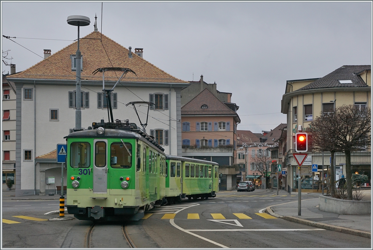 Ein A-L Regionalzug von Leysin hat Haltstelle Aigle-Place-du-Marché hinter sich gelassen und fährt nun auf der Strasse durch die Altstadt von Aigle zum Bahnhof Aigle. 

3. Jan. 2021