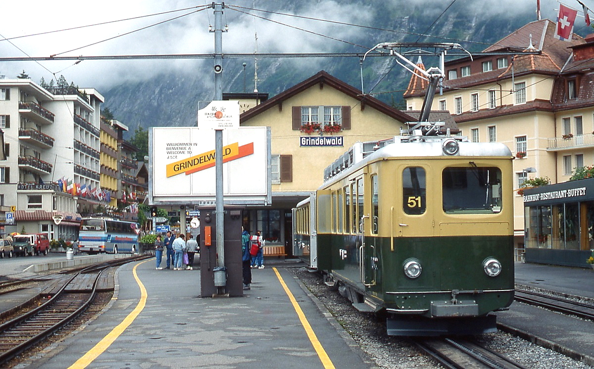 Ein ABDhe 4/4 der Wengernalpbahn steht im April 1981 abfahrbereit im Bahnhof Grindelwald, daneben die Gleise der Berner Oberland-Bahn