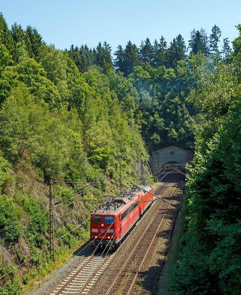 
Genau 100 Jahre nach Fertigstellung kommen sie aus dem Tunnel.... 

Die 151 029-6 (91 80 6151 029-6 D-DB) und 152 167-3 (91 80 6152 167-3 D-DB) der DB Schenker Rail Deutschland haben gerade (am 02.07.2015) gemeinsam als Lz den 2.652m langen Rudersdorfer Tunnel verlassen und fahren Richtung Norden. 
Einen lieben Gruß an den freundlichen Lokführer zurück.

Der Rudersdorfer Tunnel ist ein 2.652 m langer Eisenbahntunnel der Dillstrecke (KBS 445) zwischen Siegen und Haiger. Als Hauptingenieurbauwerk des nördlichen Abschnitts dieser Bahnstrecke durchsticht er die Tiefenrother Höhe (552,3 m), einem Berg des Rothaargebirges auf der Grenze von Nordrhein-Westfalen und Hessen.

Aufgrund der schwierigen Topografie und der begrenzten technischen Möglichkeiten war eine direkte Verbindung zwischen Siegen, Haiger und Dillenburg zum Zeitpunkt des Baus der Deutz-Gießener Bahn vom heutigen Köln-Deutz nach Gießen in den 1850er Jahren noch nicht möglich. Erst 1915 wurde die direkte Verbindung zwischen Siegen und Haiger fertiggestellt. Am 2. Juli 1915 endeten auch die Arbeiten am Tunnel, das sind nun genau 100 Jahre her.