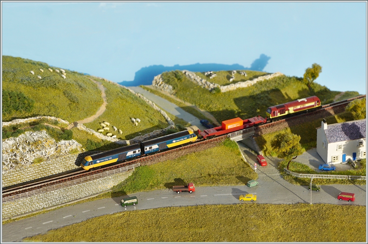 Im Detail nicht ganz vorbildlich zeigt das Bild doch einen Blick in die (nahe) Zukunft: Rail Adenture will mit seinem neuen Partner Hanson & Hall Rail Service in Grossbritannien jeweils zwei HST 125 Class 43 Dieselloks zu einer Doppellok formieren um damit hauptsächlich die neuen Class 777 Merseyrail Züge bei den nötigen Fahrten vom Hersteller zum Einsatzort zu befördern. Dazu wurden die Dieselloks 43296, 43308, 43423, 43465, 43467, 43480 und 43484 gekauft, wobei die 43 296 und 308 als Ersatzteilspender genutzt werden und aus den andern drei Doppelloks entstehen werden. Ein Habfis soll in Grossbritannien zum Adapter/-Zwischenwagen umgebaut werden, und es ist sogar geplant, die Doppelloks bei den Test Zentren in Europa verkehren zu lassen! Das Bild zeigt somit andeutungsweise im T Gauge Massstab 1:450 wie eine künftige Nutzung der aus dem Fernverkehr weitgehend ausgeschiedenen HST 125 Class 43 Dieselloks aussehen könnte. 

25. April 2021
