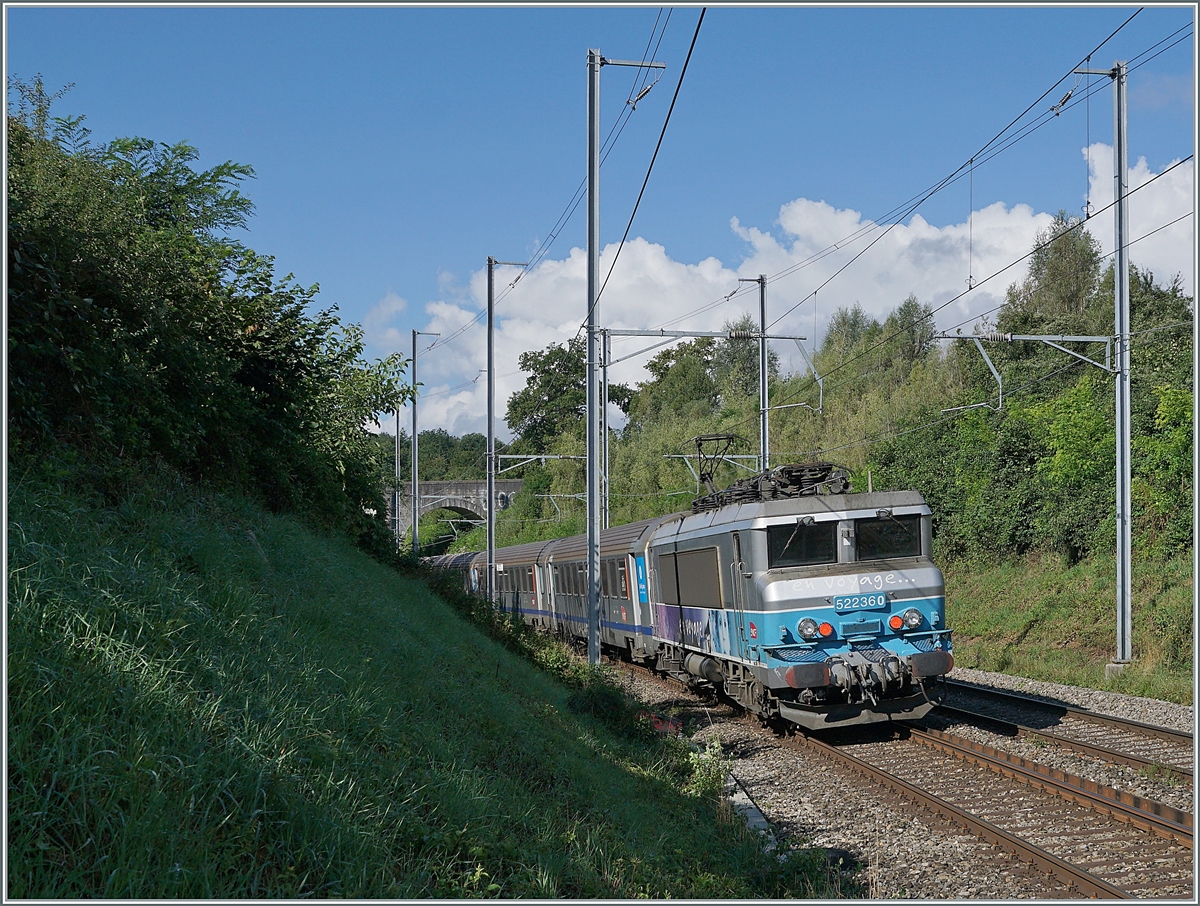 Kurz vor der Steinbogenbrücke, die sich auf dem halben Weg zwischen Satigny und Russin befindet und im Hintergrund erkennbar ist, schiebt die SNCF BB 22360  Nez cassé  ihren TER in Richtung Lyon.

2. August 2021