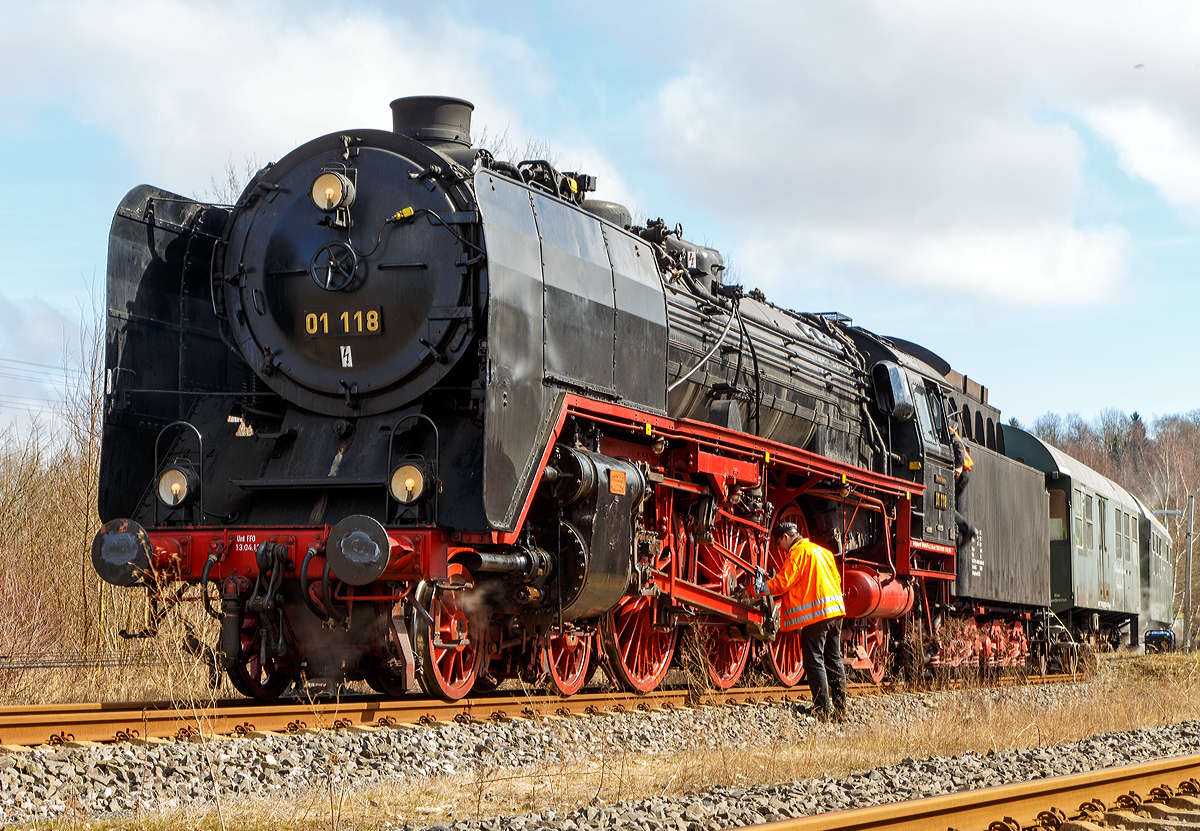 Nach der Fahrt ist vor der nächsten Fahrt, und so muss auch eine Dampflok vor der Rückfahrt wieder ordentlich geschmiert werden.

Die Zweizylinder- Schnellzuglokomotive  01 118 der HEF (Historischen Eisenbahn Frankfurt e. V.), ex DR 01 2118-6, hat am 22.03.2015 mit dem Dampfsonderzug  WESTERWALD EXPRESS  als Eilzug 25710  (Frankfurt a.M. - Limburg/Lahn - Hachenburg) den Bahnhof Hachenburg erreicht. 

Die Dampflokomotiven der Baureihe 01 waren Zweizylinder-Heißdampf-Schnellzuglokomotive für den schweren Schnellzugdienst. Sie waren die ersten in Serie gebauten Einheitsdampflokomotiven mit der Achsfolge 2’C1’ (auch Pacific genannt). Einige Lokomotiven der Baureihe 01 wurden in den 1960-er Jahren von der Deutschen Reichsbahn rekonstruiert und dann als Baureihe 01.5 eingereiht.

Zu unterscheiden von den Zweizylindermaschinen der Baureihe 01 sind die Dreizylindermaschinen der Baureihe 01.10.  Einige Zweizylindermaschinen der Baureihe 01 wurden in den 1960-er Jahren von der Deutschen Reichsbahn rekonstruiert und dann als Baureihe 01.5 eingereiht.

Die 01 118 wurde 1934 von der Lokomotivfabrik Krupp in Essen unter der Fabriknummer 1415 gebaut. Der heute mit der Lokomotive gekuppelte Tender wurde von Borsig in Berlin im Jahr 1941 mit der Fabriknummer 15117 geliefert. Der Kaufpreis für die Lokomotive mit Tender betrug damals (1934) 208.597,00 Reichsmark.

Zum Ende des zweiten Weltkrieges verblieb die Lokomotive in der damaligen Sowjetzone (späteren DDR) und wurde in den Bestand der Deutschen Reichsbahn eingegliedert. In ihren letzten Betriebsjahren bekam die Lokomotive bei der DR eine computergerechte Betriebsnummer 01 2118-6. Sie blieb von dem Umbau und Modernisierungsprogramm verschont und konnte so ihr ursprüngliches Erscheinungsbild bis zur Übernahme durch die Historische Eisenbahn Frankfurt e.V. erhalten. Bis zu ihrem Erwerb 1981 legte sie laut Betriebsbuch insgesamt stolze 3.559.271 km zurück. 

Technische Daten der Schnellzug - Dampflokomotive 01 118:
Spurweite: 1.435 mm
Bauart: 2`C1`h2
Treibraddurchmesser:  2.000 mm
Laufraddurchmesser vorn / hinten: 1.000 mm / 1.250 mm
Länge über Puffer: 23.940 mm
Zylinderdurchmesser: 600 mm
Kolbenhub: 660 mm
Kesselüberdruck: 16 bar
Höchstgeschwindigkeit vorwärts /rückwärts: 130 / 80 km/h
Leistung: 1.648 kW (ca. 2.240 PS)
Rostfläche: 4,32 m²
Verdampfungsheizfläche: 247,15 m²
Überhitzerheizfläche: 86,5 m²
Achslast max.: 20,0 t
Lokdienstgewicht: 111,3 t
Fahrzeugdienstgewicht (Lok mit Tender): 170,6 t
Wasservorrat:  34 m³ 
Kohlevorrat: 10 t

Quelle: HEF
