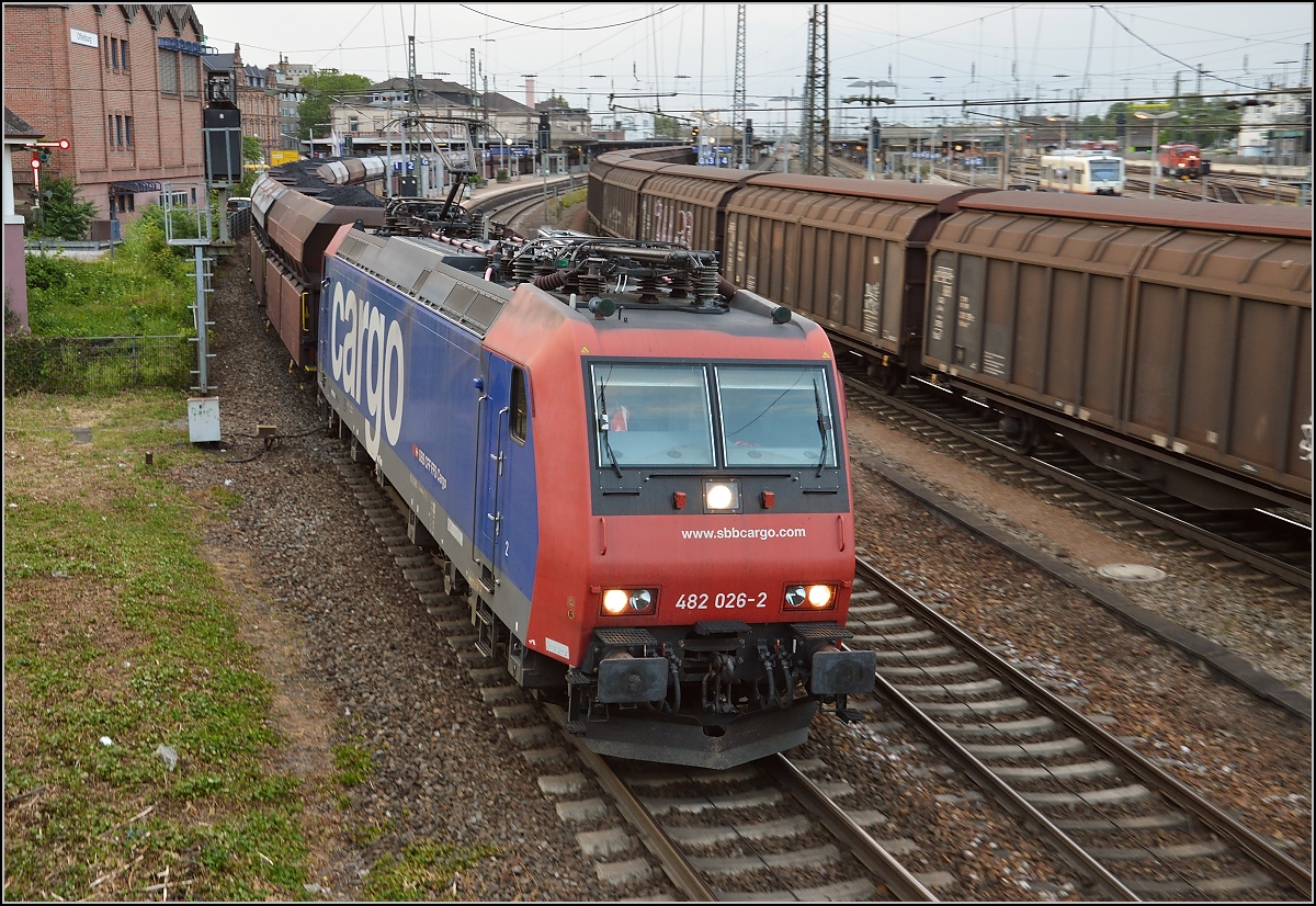 Nach der Überholung durch einen ICE nach Basel nimmt Re 482 026-2 mit ihrem Güterzug wieder Fahrt auf. Offenburg, Juni 2015.