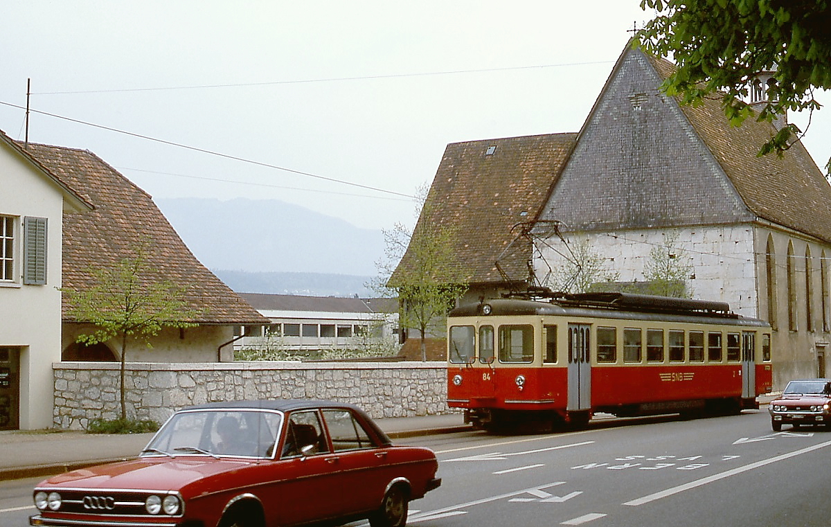Passt gerade so in die L�cke zwischen den Pkw: Be 4/4 84 der SNB f�hrt im Mai 1980 auf der Baselstra�e in Solothurn an der St.-Josefs-Kirche vorbei in Richtung Bahnhof