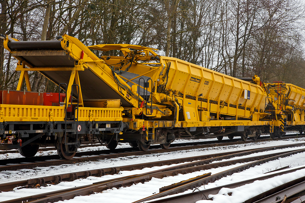 Plasser & Theurer Material-, Förder- und Siloeinheiten MFS 38 (teilweise BSW 2000 - Bunker-Schüttgut-Wagen genannt) der HERING Bahnbau, Burbach, Nr. 3, Schweres Nebenfahrzeug Nr. D-HGUI 99 80 9552 121-2, ex 97 19 22 550 17-5, ist am 11.12.2021 auf dem Betriebshof der Westerwaldbahn (WEBA) auf der Bindweide bei Steinebach/Sieg abgestellt.

Diese MFS 38 wurde 1993 von Plasser & Theurer gebaut, wobei als Fahrgestell ein vierachsiger ehemaliger Drehgestell-Flachwagen der Gattung Rs 680 (ex SSlmas 53), der 1962 von M.A.N. im Werk Nürnberg unter der Fabriknummer 146868 gebaut wurde, Verwendung fand. Diese Wagen wurden Plasser & Theurer vom Kunden beigestellt. 

TECHNISCHE DATEN:
Maschinenart: Material-Förder-Siloeinheit MSF 38
Hersteller: Plasser & Theurer
Spurweite: 1.435 mm (Normalspur)
Anzahl der Achsen: 4 (in 2 Drehgestellen)
Länge über Puffer:19.900 mm
Gesamtlänge mit Übergabeband: 23.550 mm
Drehzapfenabstand: 13.000 mm
Achsabstand im Drehgestell: 2.000 mm
Laufraddurchmesser: 1.000 mm (neu)
Drehgestell-Bauart: Minden Dorstfeld-Drehgestell 931 / 932
Breite: 2.890 mm
Höhe: 4.280 mm
Eigengewicht: 38 t
Max. Zuladung (Nutzlast): 42 t
Ladevolumen: 38 m³
Höchstgeschwindigkeit: 100 km/h (geschleppt)
Kleister befahrbarer Gleisbogen: R=120 m (angeschrieben)
Bremse: KE – GP
Motor: luftgekühlter Deutz Dieselmotor vom Typ F6L 912 F
Leistung: 82 kW
Dieseltankvolumen: 750 l
Übergabeband: +/- 45 Grad schwenkbar.
Entladezeit: 3,5 Minuten
Entladeabstand von Gleismitte: max. 4,5 m
Die Förderbänder sind in folgenden Geschwindigkeiten regelbar:
Siloband: 1. Gang (Speichern)   0 - 0,028 m/s / 2. Gang (Durchfördern)  0 - 0,140 m/s
Übergabeband: 0 - 1,000 m/s

Einsatz und Arbeitsweise:
Bei diesem MFS 38 (ohne nachfolgendes „D“) ist das Übergabeband beidseitig zum Gleis um 45 Grad schwenkbar, so ist ein  Entladen nebens Gleis oder zum Nachbargleis möglich. Die MSF 38 haben ein Fassungsvermögen 38 m³ bzw. eine Nutzlast von 42t, bei einem Eigengewicht von 38t. Die Förderbänder werden hydraulisch angetrieben. Der Antrieb des Hydraulikaggregates erfolgt durch einen luftgekühlten Deutz Dieselmotor vom Typ F6L 912 mit einer Leistung von 82 kW.

Mit den Materialförder- und Siloeinheiten können unterschiedliche Schüttgüter wie beispielsweise Abraum, Planum- und Frostschutzmittel oder Bettungsstoffe unkompliziert, geladen, gefördert, gespeichert und entladen werden. Das Abraumverladesystem ist weitestgehend automatisiert und benötigt zur Bedienung nur wenig Personal. Das System verfügt zudem über eine autarke Energieversorgung (durch Dieselmotore). Ein unabhängiges Entladen ist durch schwenkbare Übergabebänder an jeder geeigneten Stelle möglich. Die MFS-Wagen können in Kombination mit einer Beladestation in beliebiger Anzahl aufgereiht und vor Kopf be- und entladen werden.

Am Boden jedes MFS 38 befindet sich ein über die ganze Wagenbreite gehender Fördergurt und an der Stirnseite ein breites Abgabeförderband. Das Aushubmaterial fällt von der Maschine kommend auf den Bodengurt, wird zum Abgabeförderband gebracht und an die nächste Einheit übergeben. Dieser Vorgang wiederholt sich, bis die am weitesten entfernte Siloeinheit erreicht wird. Bei dieser hintersten Siloeinheit ist das Abgabeförderband an der Stirnseite des Wagens in Ruhestellung. Auch der Fördergurt am Boden des Wagens ist so lange in Ruhestellung, bis die obere Füllgrenze erreicht ist. Dann wird der Fördergurt in Bewegung versetzt und dadurch im Übergabebereich freier Raum für die weitere Beladung geschaffen. Durch die dem Fülltempo angepasste Geschwindigkeit des Fördergurts wird die ganze Siloeinheit vollständig gefüllt. Das Fassungsvermögen einer Siloeinheit beträgt 38 Kubikmeter.

Nach Füllung einer Teilgruppe des Abraumzuges kann diese von der Restgruppe abgekuppelt werden, zu einer Entladestelle gefahren und dort entleert werden, während die Restgruppe des Abraumzuges noch befüllt wird. Das Entladeband ist nach beiden Seiten ausschwenkbar. Die Entladung kann dabei auf einer Deponie erfolgen oder es können LKW's oder Waggons am Nachbargleis beladen werden. Die MFS 38 (ohne nachfolgendes „D“) des Abraumzuges können durch Ausschwenken aller Abgabeförderbänder gleichzeitig entleert werden. Die Entladung eines Wagens dauert ungefähr 3,5 Minuten.
