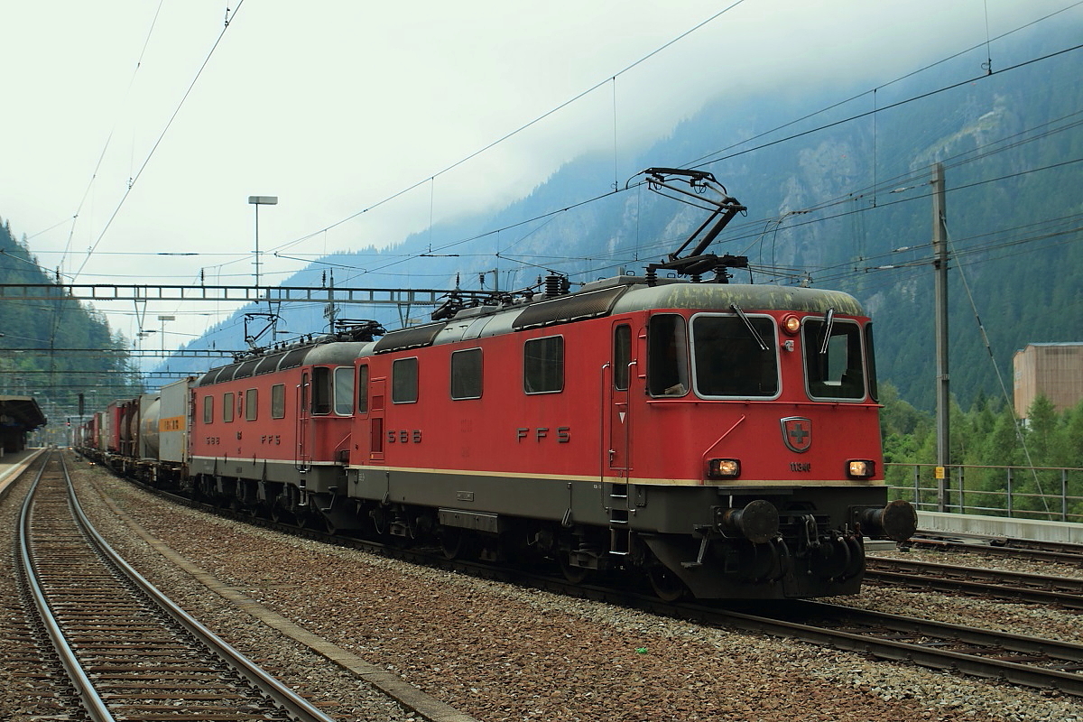 Re 4/4 II 11340 und eine Re 6/6 durchfahren mit einem Güterzug in Richtung Süden den Bahnhof Göschenen