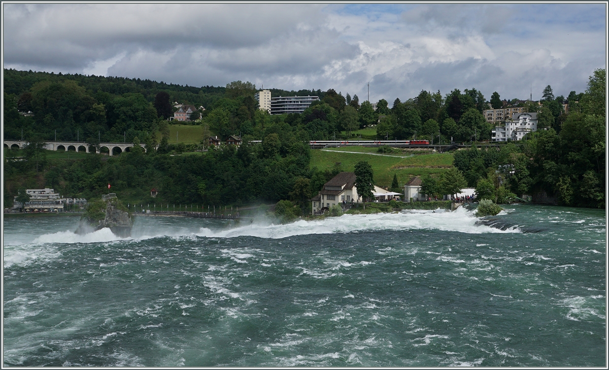 Rheinfall - während der Rhein zu Tale stürzt, fährt eine SBB Re 4/4 mit einem IC kurz vor Neuhausen in Richtung Schaffhausen.

18. Juni 2016
