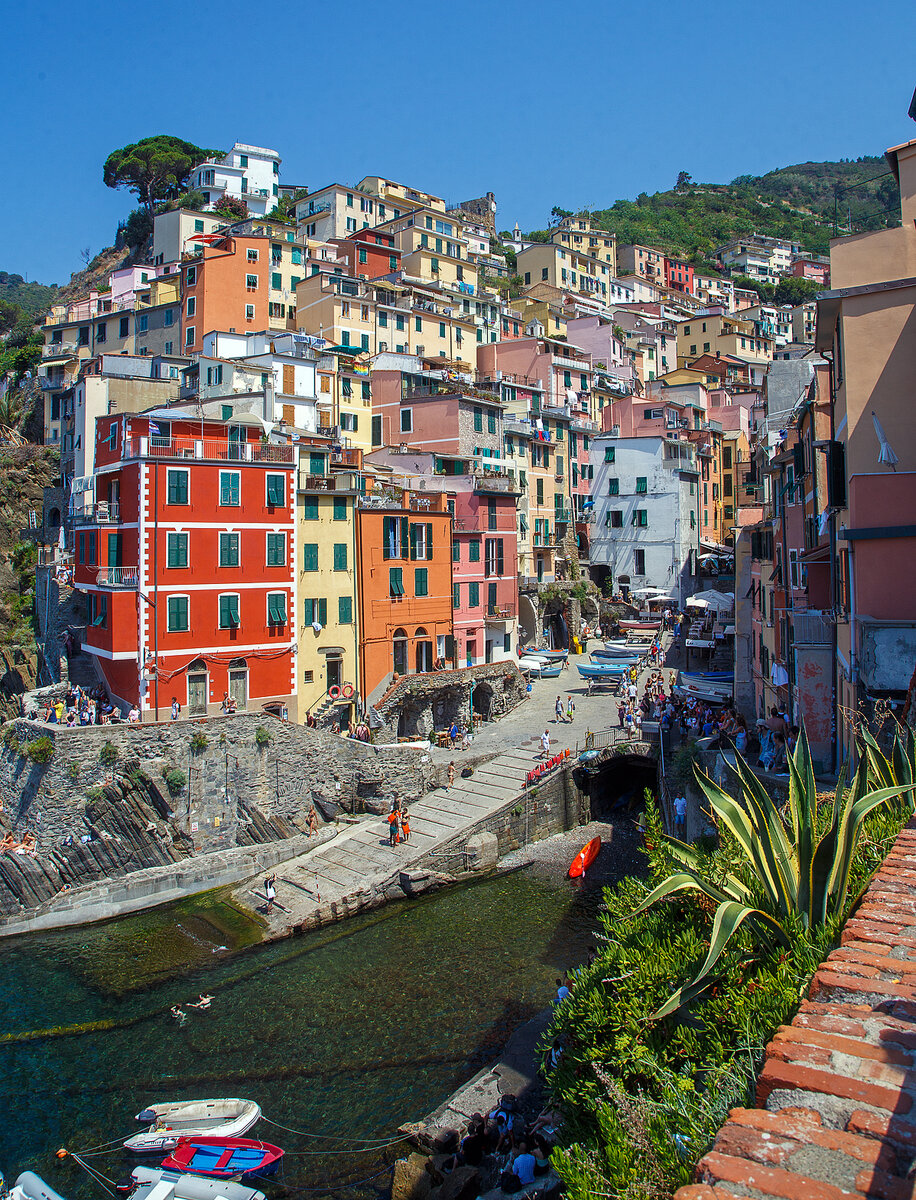 Riomaggiore (Cinque Terre) am 21.07.2022, hier der Blick auf die Bucht und das Zentrum mit den sich gegeneinander auft�rmenden bunten Hausfassaden in allen m�glichen Farbt�nen.