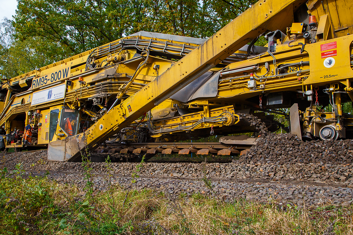 
Unter dem Gleis hindurch geschaut....
Detailbild vom Schotteraushub und ca. 2m dahinter (links) die Schotterrückführung (recycelt) der Plasser & Theurer Bettungsreinigungsmaschine RM 95-800 W der MGW Gleis- und Weichenbau-Gesellschaft mbH & Co. KG (Berlin), die auf der Hellertalbahn (KBS 462) im Einsatz ist, hier am 20.10.2020 in Neunkirchen-Altenseelbach.
