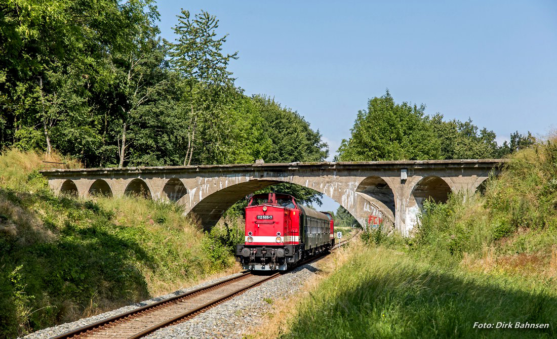 V100-Planeinsatz auf R�gen... Die gr��te deutsche Insel ist ja immer eine Reise wert. Neben dem  Rasenden Roland  sind dort hin und wieder aber auch historische Fahrzeuge auf der Regelspur unterwegs. So wie am vergangenen Wochenende, als die Personenz�ge zwischen Bergen und Lauterbach Mole mit 112 565-7 und 112 703-4 gefahren wurden. Am 23.08.2015 unterquerte die Garnitur gerade in Putbus die ehemalige Kleinbahnstrecke nach Altef�hr...
