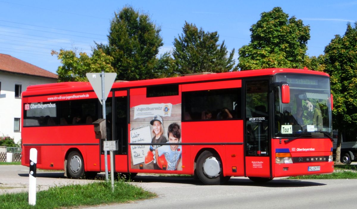 Wie mehrere Busse seiner Flotte hat Hinmüller Reisen aus Oberflossing bei Polling diesen Setra S 315 UL im Design der RVO / DB Oberbayernbus gestaltet und mit einer Werbefolie der Jugendfeuerwehr versehen. Dieses Exemplar ist bei Setra im Jahr 2000 vom Band gelaufen und hat 55 Fahrgastsitzplätze (mit kippbarer Sitzbank am Mitteleinstieg; Setra-Überlandbestuhlung Modell Special-Class mit Sicherheitsgurten) plus 2 Reiseleitersitze. Vorne, rechts und hinten ist jeweils eine LAWO-Matrix eingebaut. Der Antriebsstrang besteht aus dem Reihensechszylinder Typ MB OM 447 hLA mit 184 kW (250 PS) und dem Sechsgang-Handschaltgetriebe ZF S 6-85.
Abgelichtet wurde der Bus am Mittag des 17. 9. 2015 an der Wendeschleife vor der Inn-Apotheke in Kraiburg/Inn, als er aus Waldkraiburg kommend auf der RBO-Linie 6224 Kurs 034 unterwegs war.