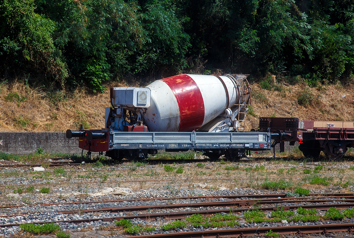 Zweiachsiger Niederflur-Flachwagen mit Seitenwandklappen, IT-RFI 140 049-3, mit darauf befindlichen Betonmischer (Fahrmischer), abgestellt am 16.07.2022 beim Bahnhof Agropoli (Region Kampanien – Italien). Aufnahme aus einem IC durch die Scheibe.

TECHNISCHE DATEN (laut Anschriften):
Spurweite: 1.435 mm
Achsanzahl: 2
Länge über Puffer: 8.560 mm
Achsabstand: 4.500 mm
Höchstgeschwindigkeit: 55 km/h
Eigengewicht: 10.200 kg
Max. Zuladung: 21.800 kg (einschl. Eigengewicht des Mischers)