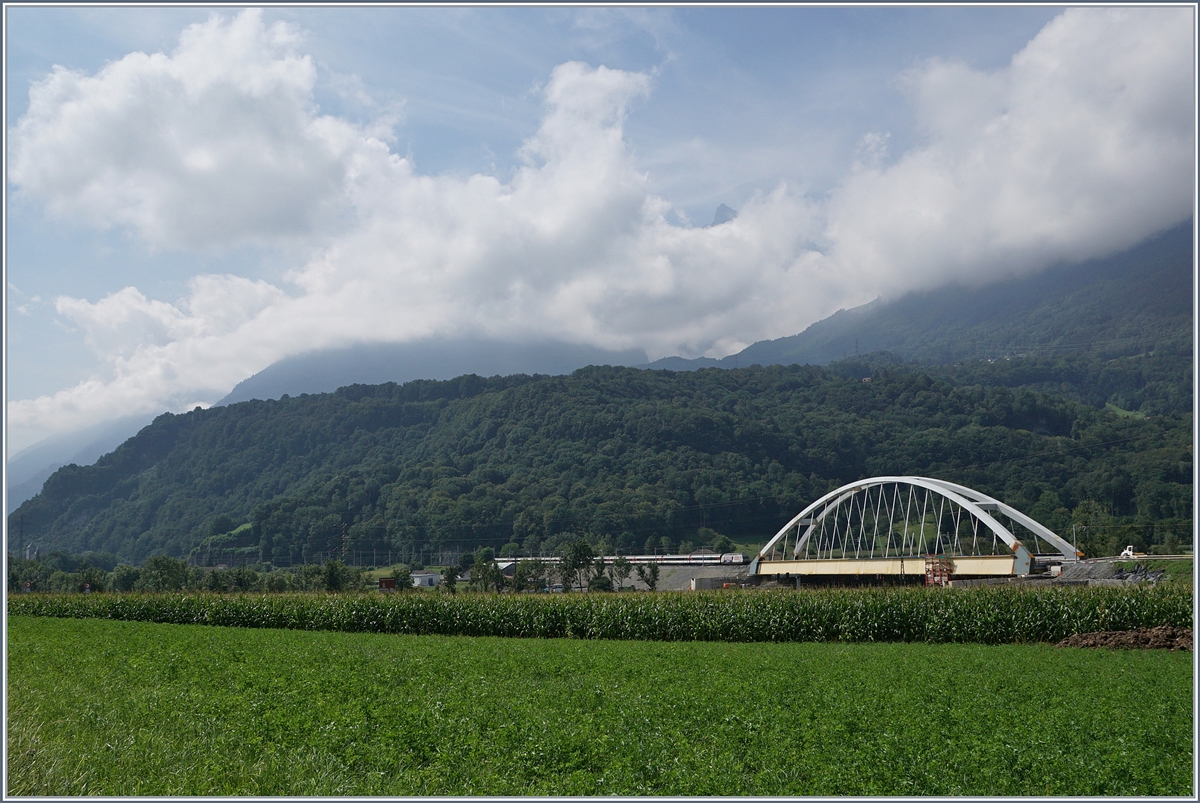 Zwischen Bex und St-Maurice überquert die Strecke Lausanne Birg die Rhone. Die alte Gittereisenbrücke wird nun durch eine sehr gefällige und unübersehbare Neukonstruktion ersetzt. Zu Zeit ist die alte Brücke schon nicht mir in Betrieb und der Verkehr verläuft einspurig über die neue Brücke, wobei vor und nach der Brücke das nördliche Gleis, dann auf der Brücke das Südliche Gleis benutzt wird, so dass die Brücke noch verschoben werden muss. Leider ist es nicht einfach, einen einigermasen guten Fotostandpunkt zu finden. Das Bild zeigt den von einer SBB Re 460 geschobenen IR 1717 von Lausanne nach Brig. 
19. August 2016
