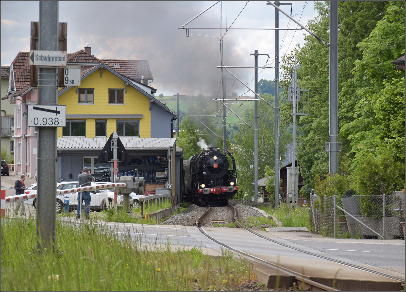 150 Jahre Emmentalbahn. 

141-R-1244 auf dem Rückweg von der grossen Emmentalrundfahrt anlässlich des Jubiläums. Auf dem Bahnübergang Luezerner Strasse in Huttwil beschleunigt sie eindrucksvoll den Zug die kurze Rampe zur Wasserscheide hinauf. Mai 2025.

Der ungewöhnlich abgesteckte Bahnübergang lässt noch den Streckenverlauf der Huttwil-Eriskirch-Bahn vermuten, die heute zur Gänze abgebaut ist. An dieser Stelle trennte sich die Stichstrecke von der Huttwil-Wolhusen-Bahn. 