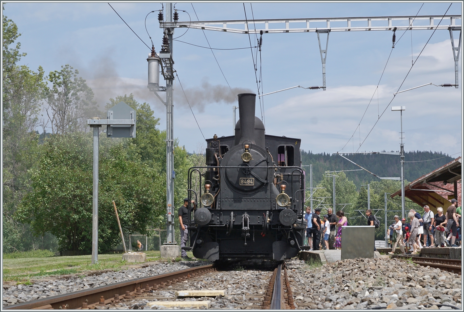  Bitte Einsteigen!  Das CTVJ (Compagnie du Train à Vapeur de la Vallée de Joux) Tigerli E 3/3 8494 (UIC 90 85 0008 494-6) der SLM mit Baujahr 1909 wartet in Le Pont mit seinem Sonderzug auf die Gäste für die Fahrt nach Le Brassus. Das Bild entstand auf dem geöffneten Bahnübergang.

23. Juli 2023