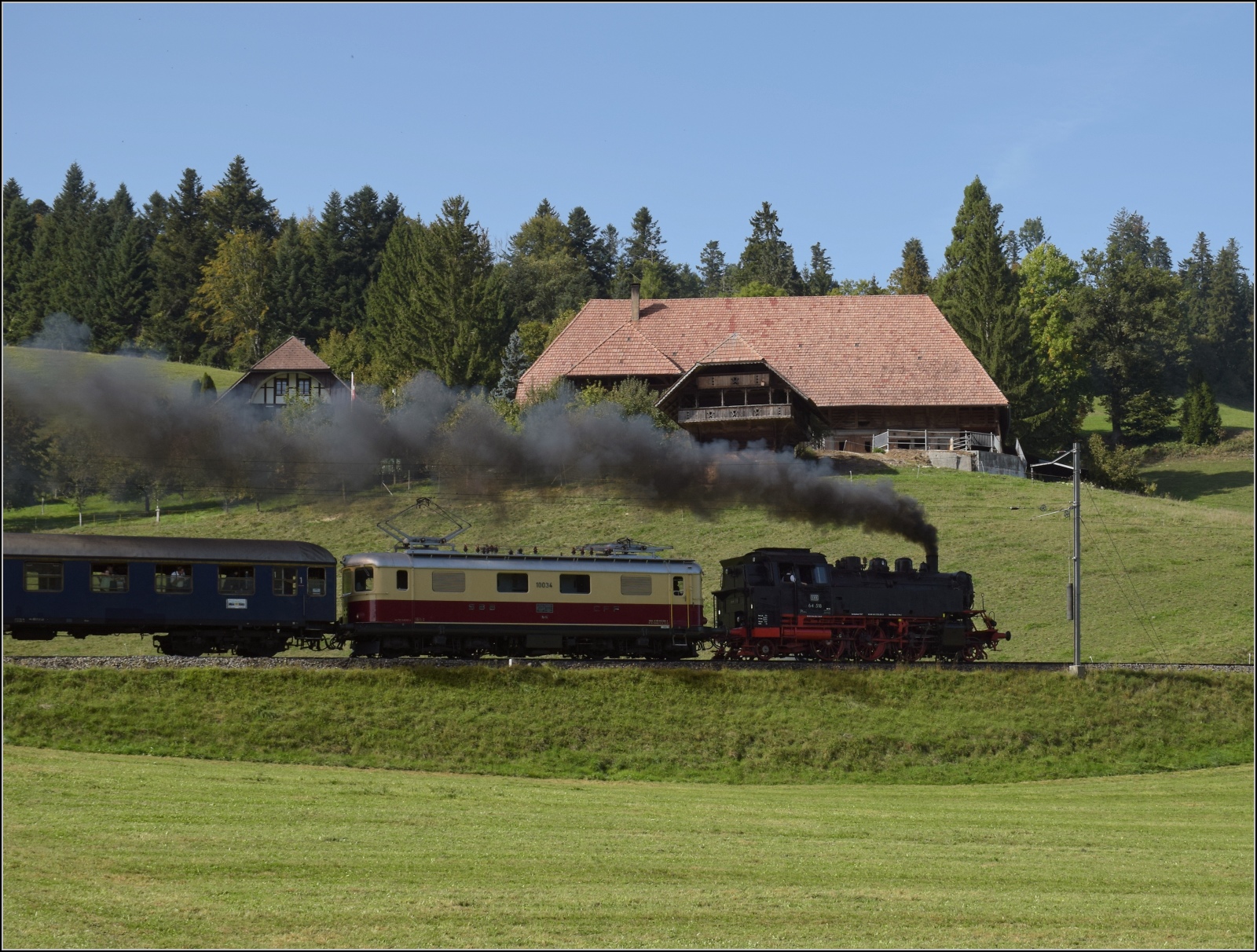 Dampftage Huttwil mit frisch genesenem Bubikopf. 

In Wydithub geht es für 64 518 und Re 4/4 I 10034 die steile Rampe nach Weier hinauf. Oktober 2023.