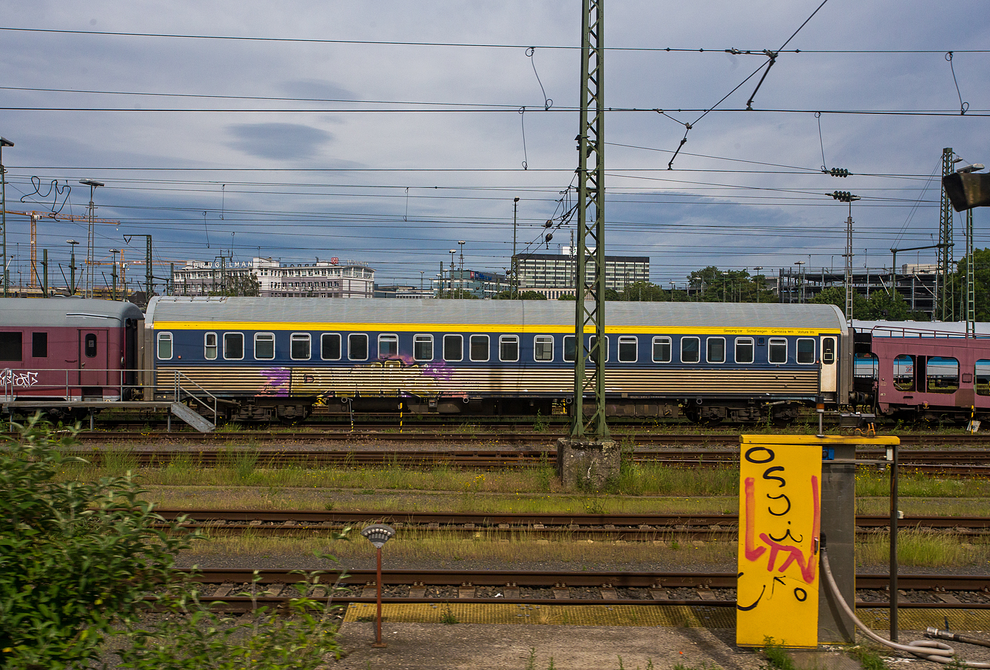 Der leider beschmierte Schlafwagen der Gattung WLAB (CIWL Typ MU '64), NL-MSM 61 84 06-70 617-1 der MSM Gruppe Inh. Niko Maedge e.K. (Köln) abgestellt am 26 Mai 2024 im Zugverband in Köln-Deutzerfeld, aus einem Zug heraus fotografiert, leider mit einem Mast davor.

Der Wagen vom CIWL Typ MU '64 wurde 1966 von der WMD - Waggon- und Maschinenbau GmbH Donauwörth (ab 1971 MBB - Messerschmitt-Bölkow-Blohm) gebaut und an die Compagnie Internationale des Wagons-Lits (CIWL), seit 1967 Compagnie Internationale des Wagons-Lits et du Tourisme (CIWLT, deutsch Internationale Schlafwagen- und Touristik-Gesellschaft), geliefert. Die CIWL/CIWLT ist das älteste europäische Unternehmen zum Betrieb von Schlafwagen, Speisewagen und Luxuszügen.  

Der Schlafwagen wurde CIWL 4794 bezeichnet/geführt, später als CIWLT 51 66 06-80 094-9 (der Code 66 ist hier für das Eigentumsmerkmal der CIWLT). Später ging der Wagen an die belgische Staatsbahn NMBS / SNCB als 71 88 72-80 617-6, 2003 ging er an die Euro Express Treincharter (EETC) als 61 88 06-70 617-1 B- EETC, ab 2005/6 als 61 84 06-70 617-5 NL-EETC. Im Jahr 2016 ging er an die MSM Gruppe in Köln als NL- MSM 61 84 06-70 617-1.

Ab dem Jahr 1964 wurden etwa 100 dieser Schlafwagen vom Typ MU mit zwölf Universalabteilen, mit jeweils drei Betten pro Abteil von der CIWL in Dienst gestellt. Diese Schlafwagen sind heute noch in vielen Teilen Europas anzutreffen, teilweise im Eigentum der Bahnen, teilweise von der CIWL angemietet.

TECHNISCHE DATEN:
Gebaute Anzahl: ca. 100
Hersteller: WMB (oder FIAT)
Baujahre: an 1964
Spurweite: 1.435 mm (Normalspur)
Länge über Puffer: 26.400 mm
Wagenkastenlänge: 25.900 mm
Wagenkastenbreite: 2.820 mm
Höhe über Schienenoberkante: 4.260 mm
Drehzapfenabstand: 18.500 mm
Achsstand im Drehgestell: 2.500 mm
Leergewicht: 61 t
Höchstgeschwindigkeit: 160 km/h
Sitz- /Liegeplätze in der 2. Klasse: 36
Abteile: 12
